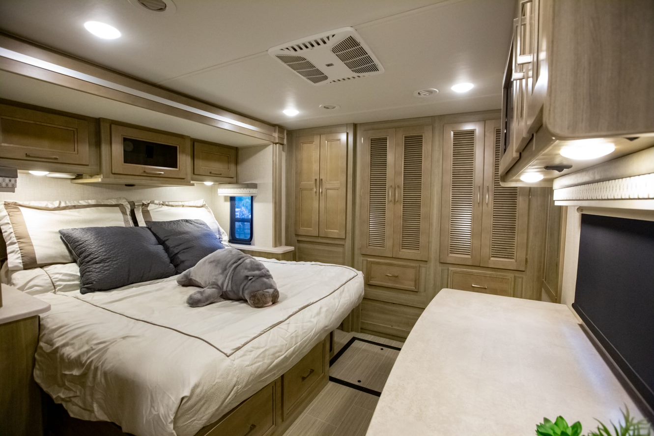 This cozy RV rental bedroom offers a comfortable bed with a manatee plushie, ample storage, and bright interior lighting.. Coachmen Other 2020