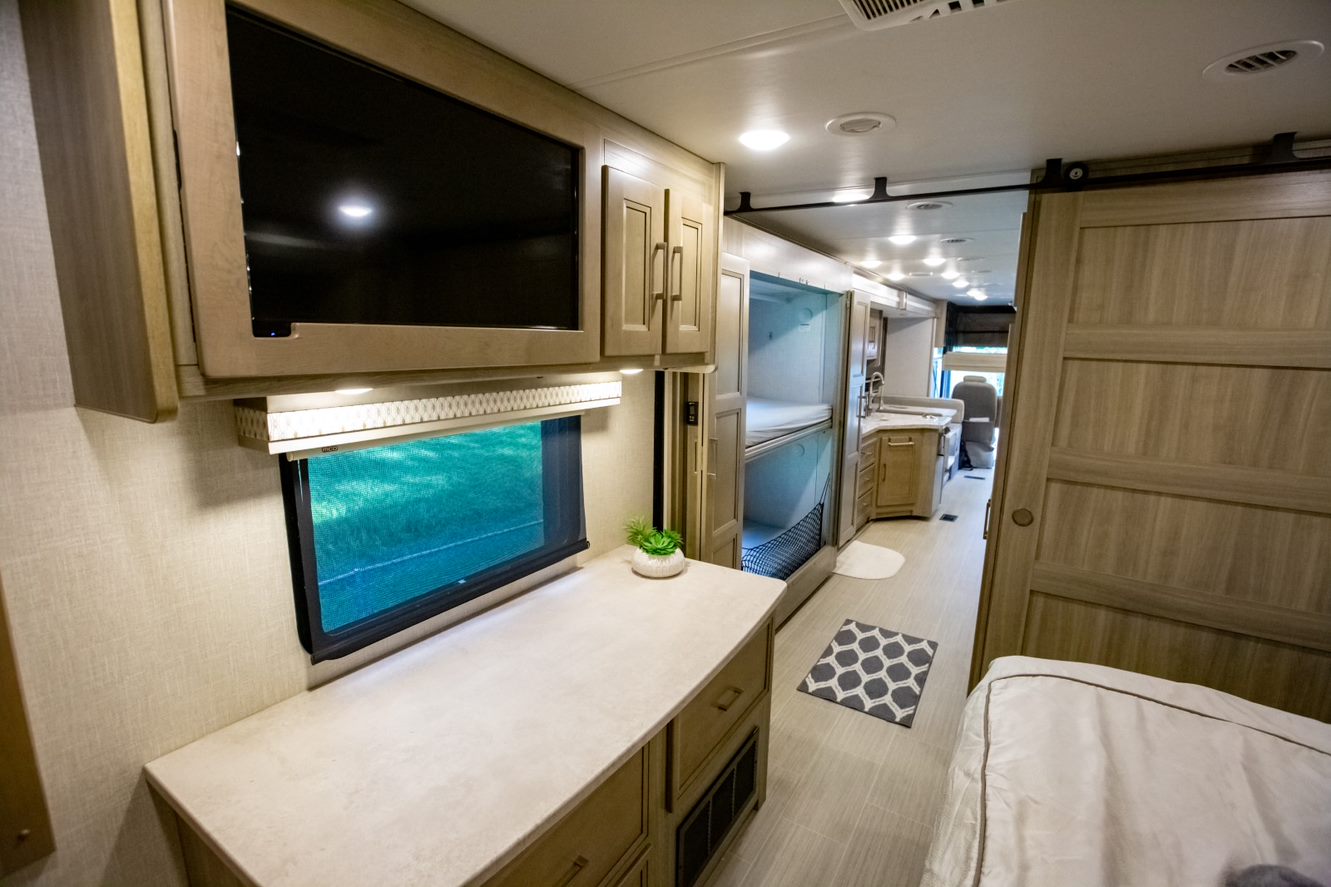 This RV rental interior reveals a modern design, with a bedroom on the right, leading past bunk beds and a kitchen to the front.. Coachmen Other 2020