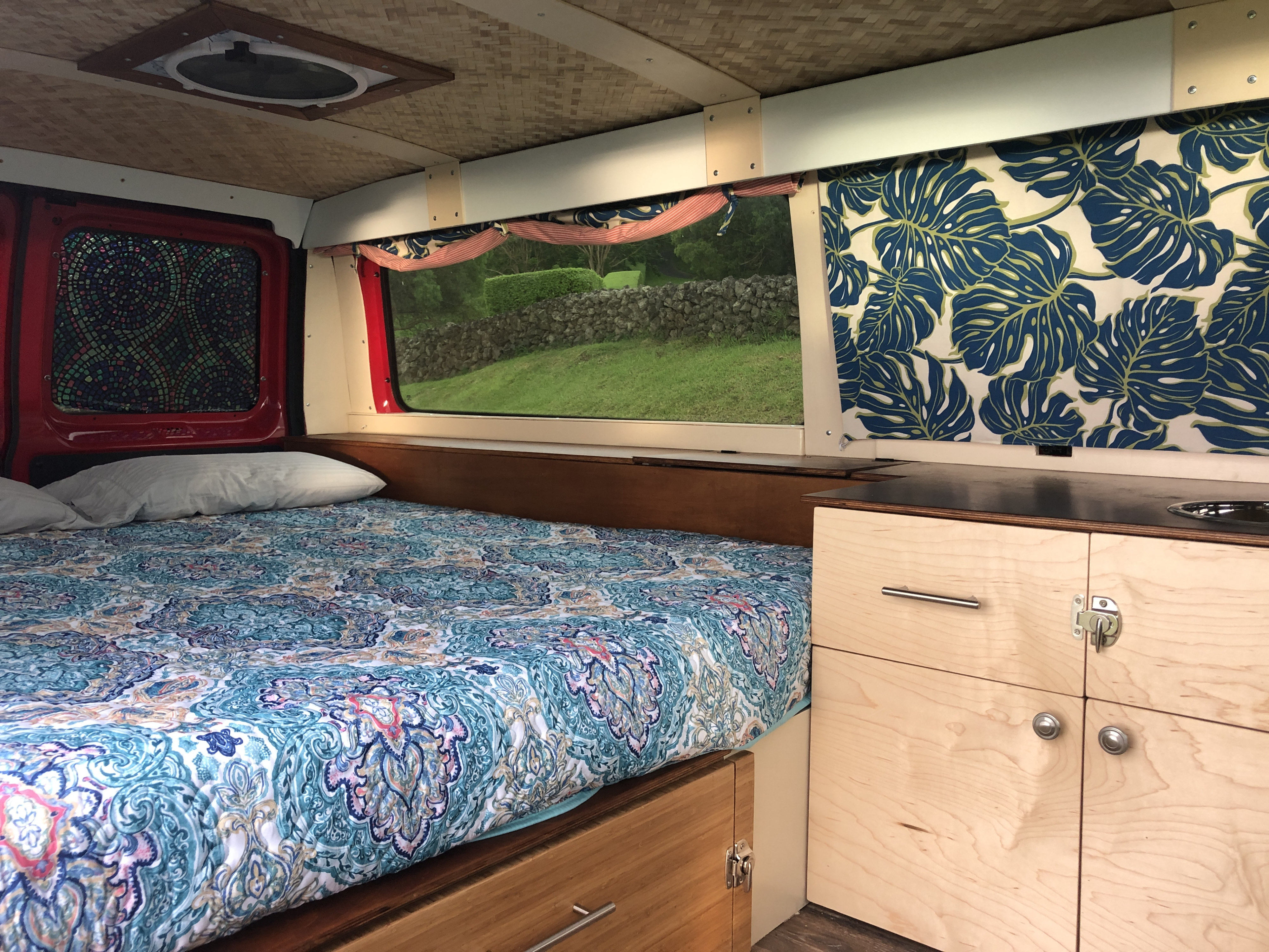 Cozy RV rental interior with bed, kitchen, and window view. Perfect for van life adventures.. Ford E150 2011
