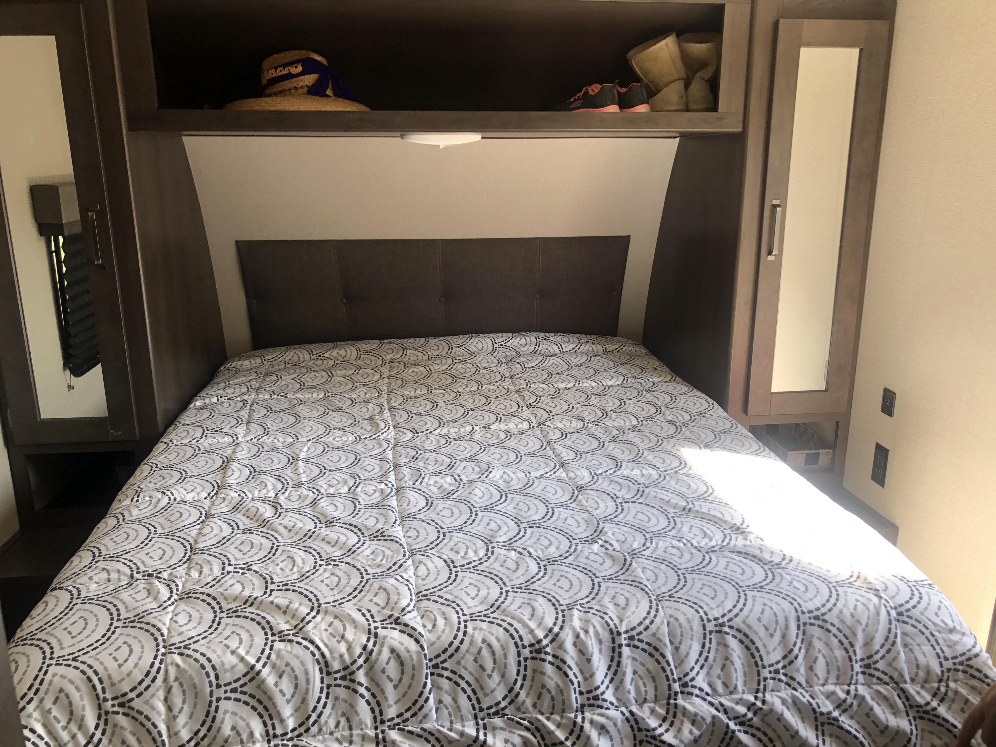 RV rental bedroom featuring a comfortable bed, overhead shelves, and mirrored side wardrobes for efficient storage.. Grand Design Other 2020