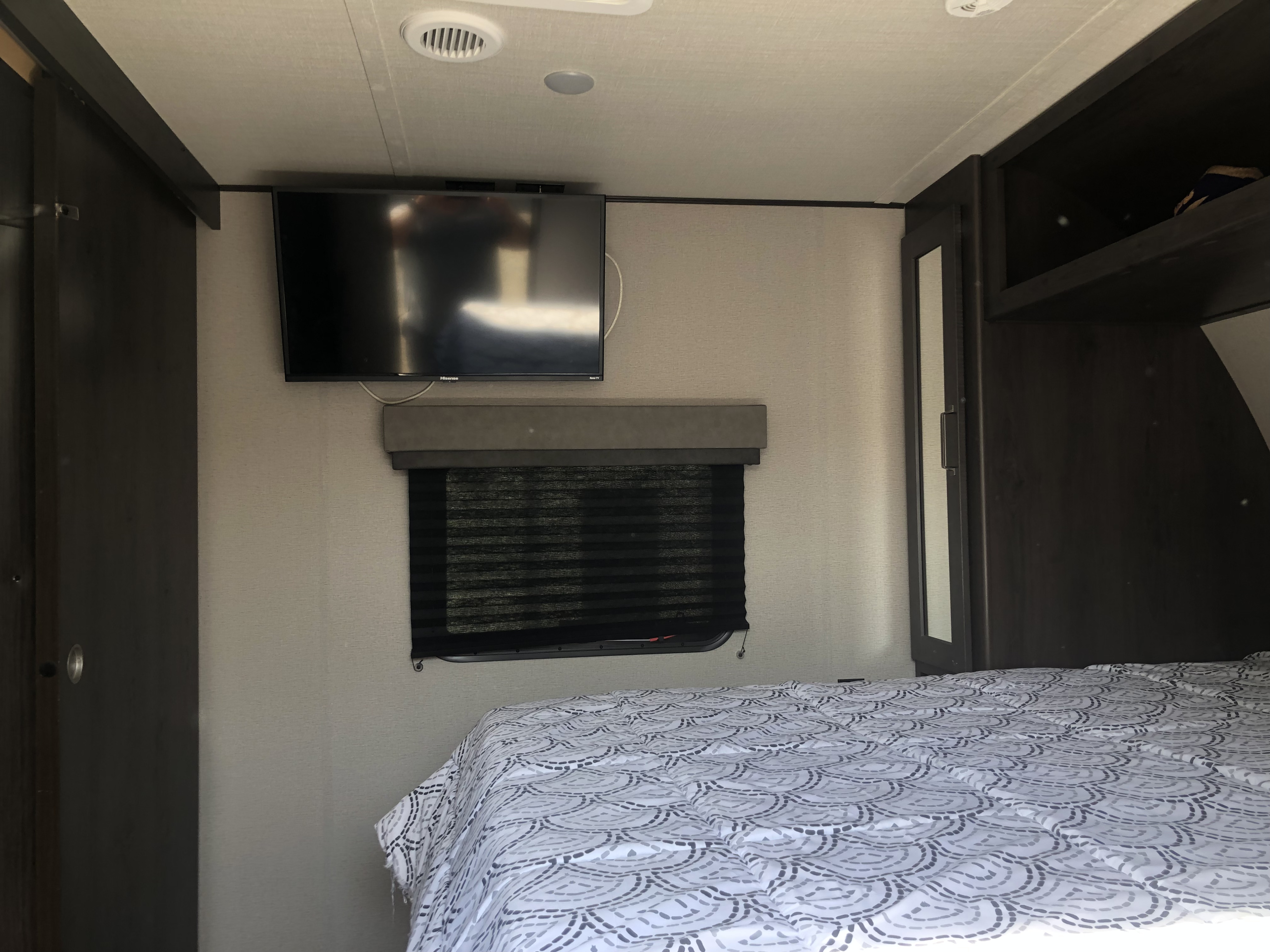 Comfortable RV rental bedroom featuring a bed, wall-mounted TV, window, and built-in storage for travel.. Grand Design Other 2020