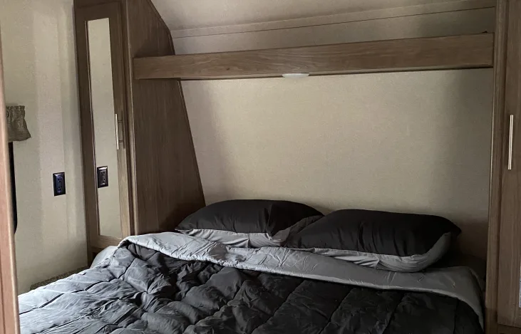 Explore a comfortable RV rental bedroom with a neat bed, storage cabinets, and built-in lighting, perfect for travel.. Keystone Hideout 2019