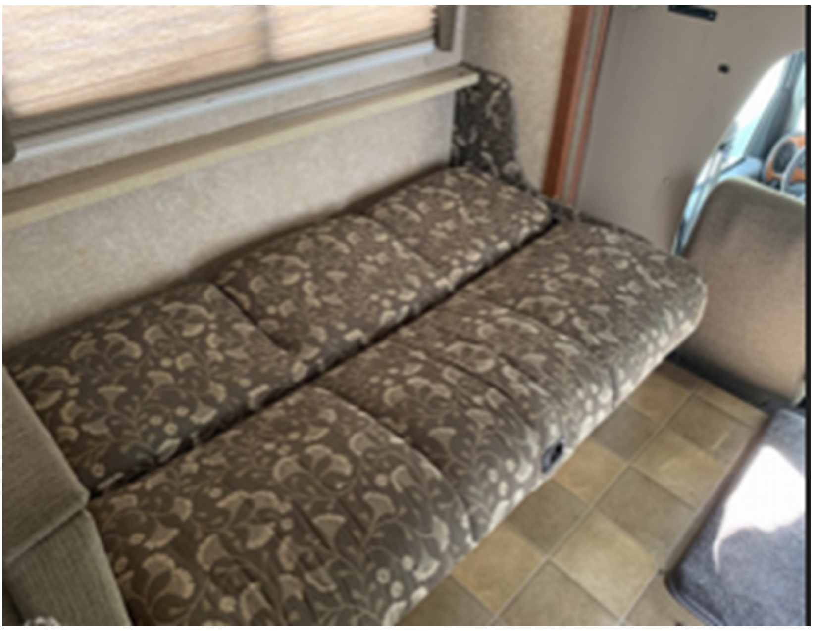 RV rental interior view: a long, patterned couch/dinette and window, with a practical tiled floor for your travels.. Thor Motor Coach Four Winds 2007