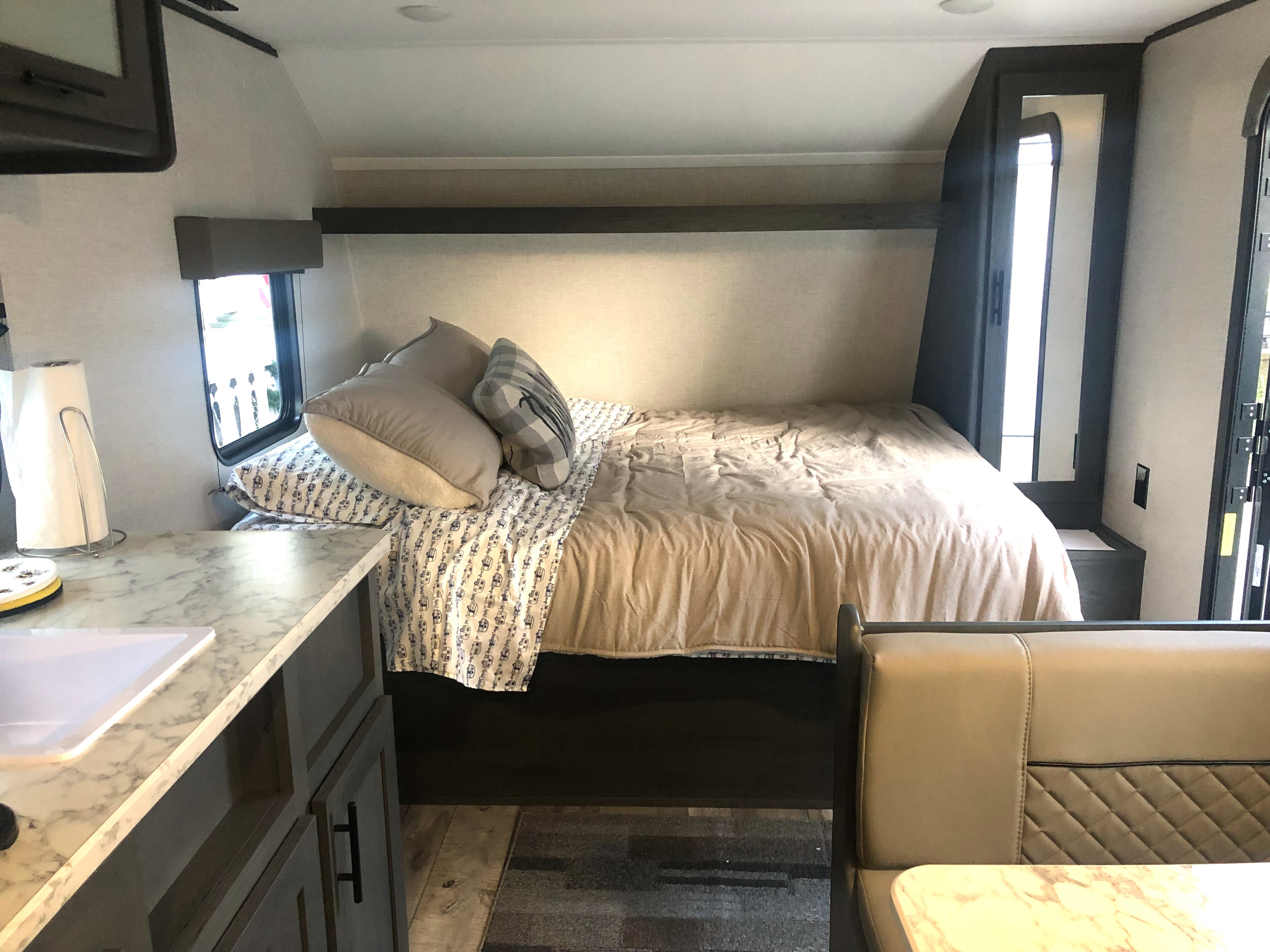 Cozy RV rental interior featuring a comfortable bedroom, compact kitchen with sink, and a dinette seating area.. Dutchman Aspen Trail 2022