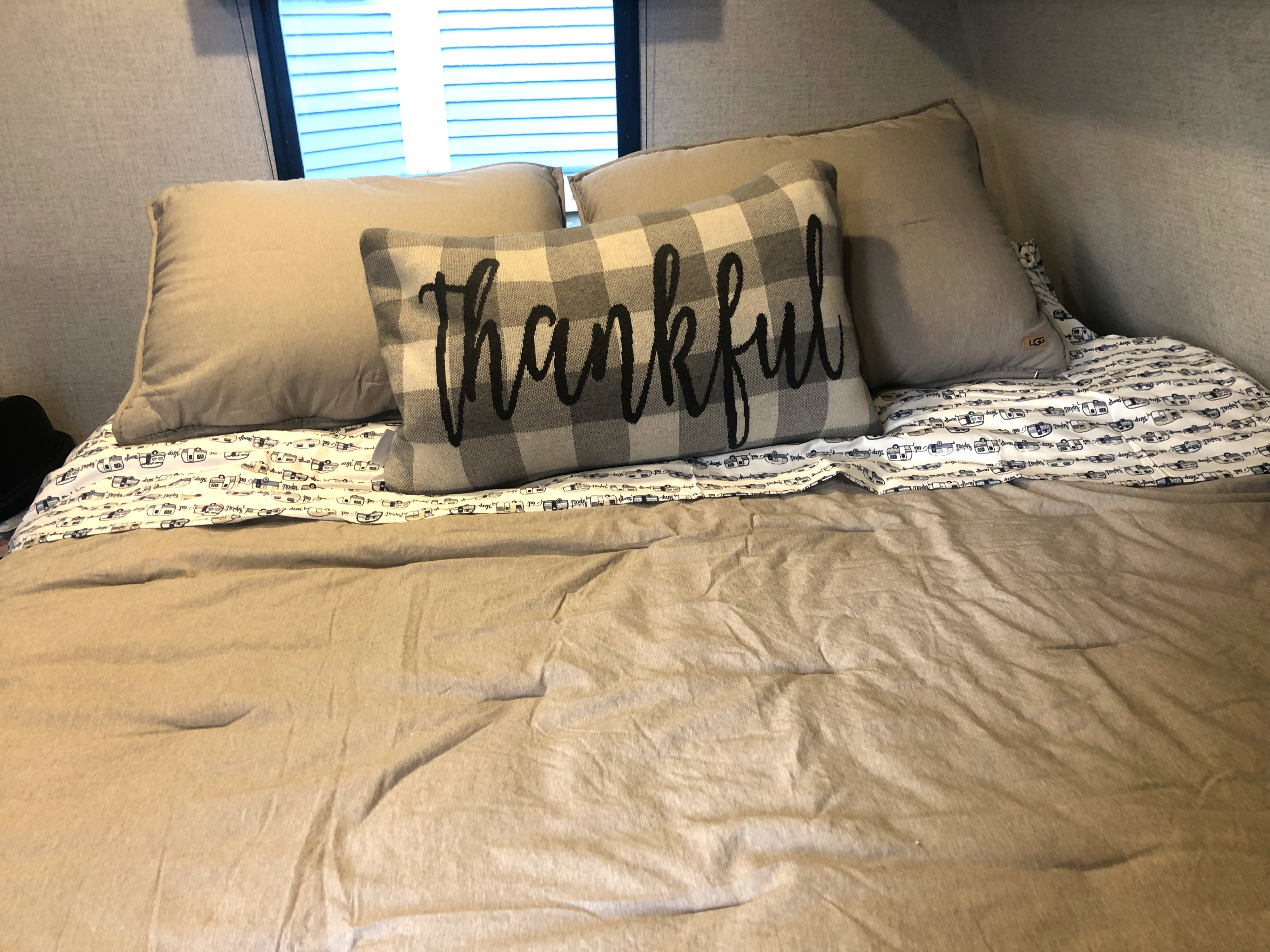 Cozy RV rental bed with "Thankful" pillow and camper-themed sheets.. Dutchman Aspen Trail 2022