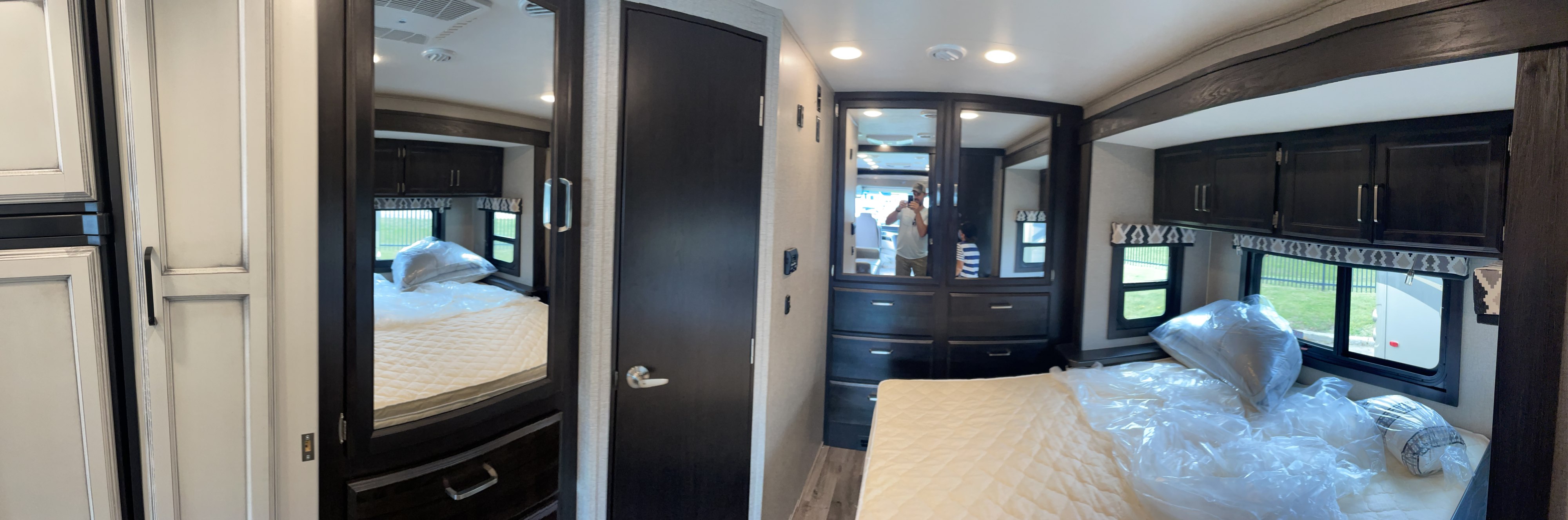 Inside an RV rental's bedroom: a clean bed with new pillows, mirrored wardrobe, and dark wood cabinets for comfortable travel.. Jayco Other 2021