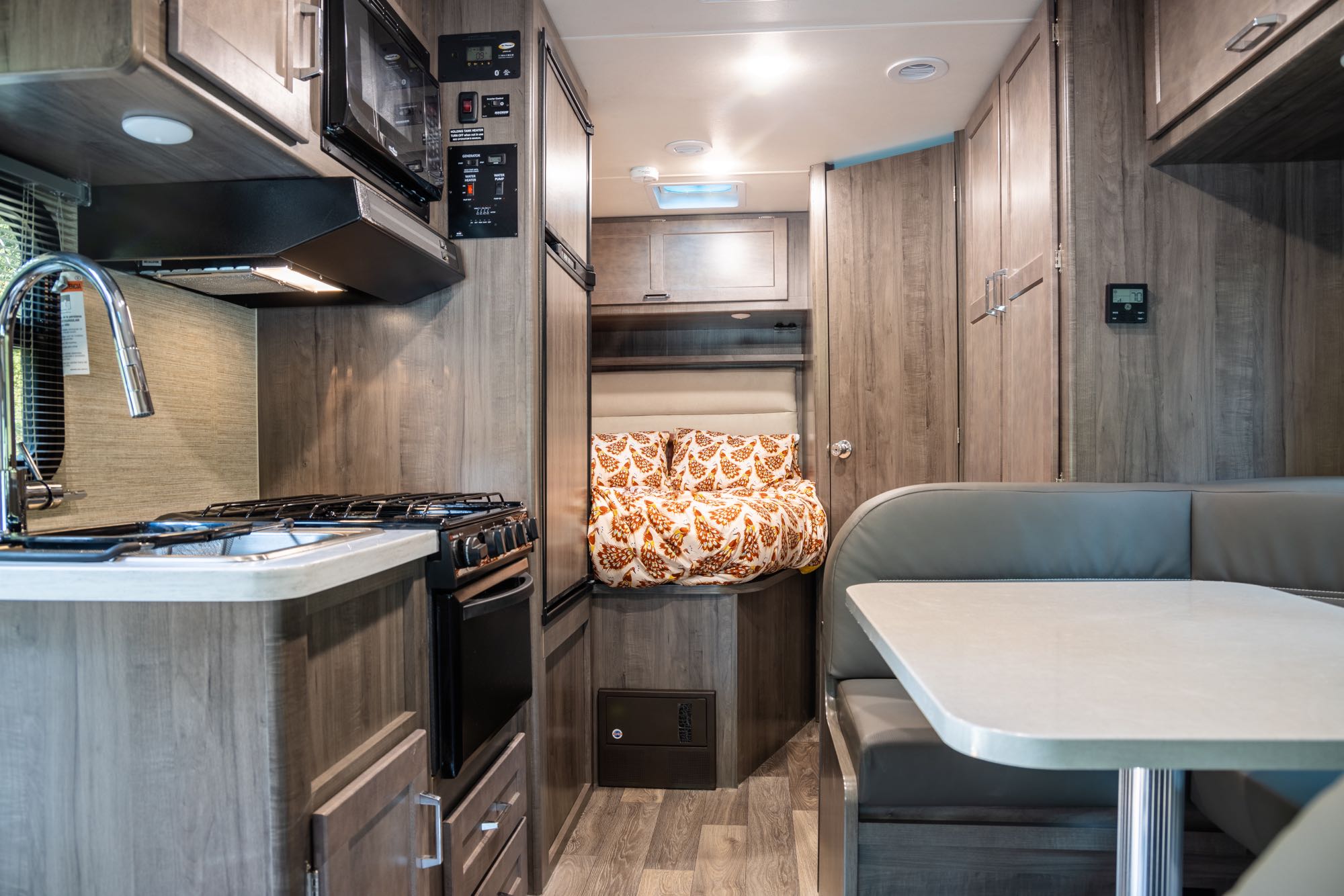 Spacious RV rental interior featuring a modern kitchen, cozy bed nook, and comfortable dinette. Perfect for your next adventure.. Winnebago Minnie Winnie 2021