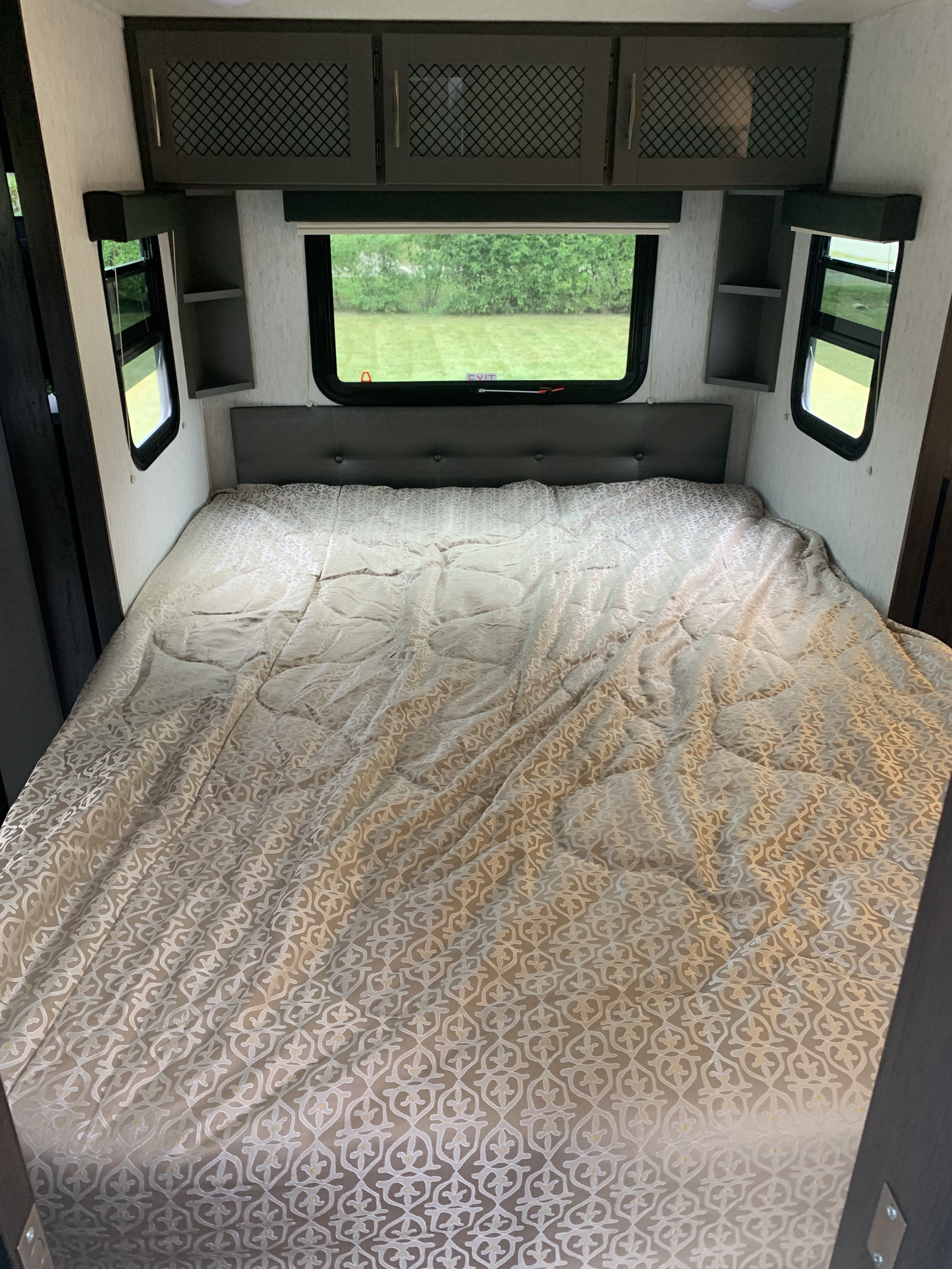 Relax in this RV rental bedroom. Features include a comfy bed, headboard, ample windows with views, and overhead storage.. Grand Design Momentum Toy Hauler 2022