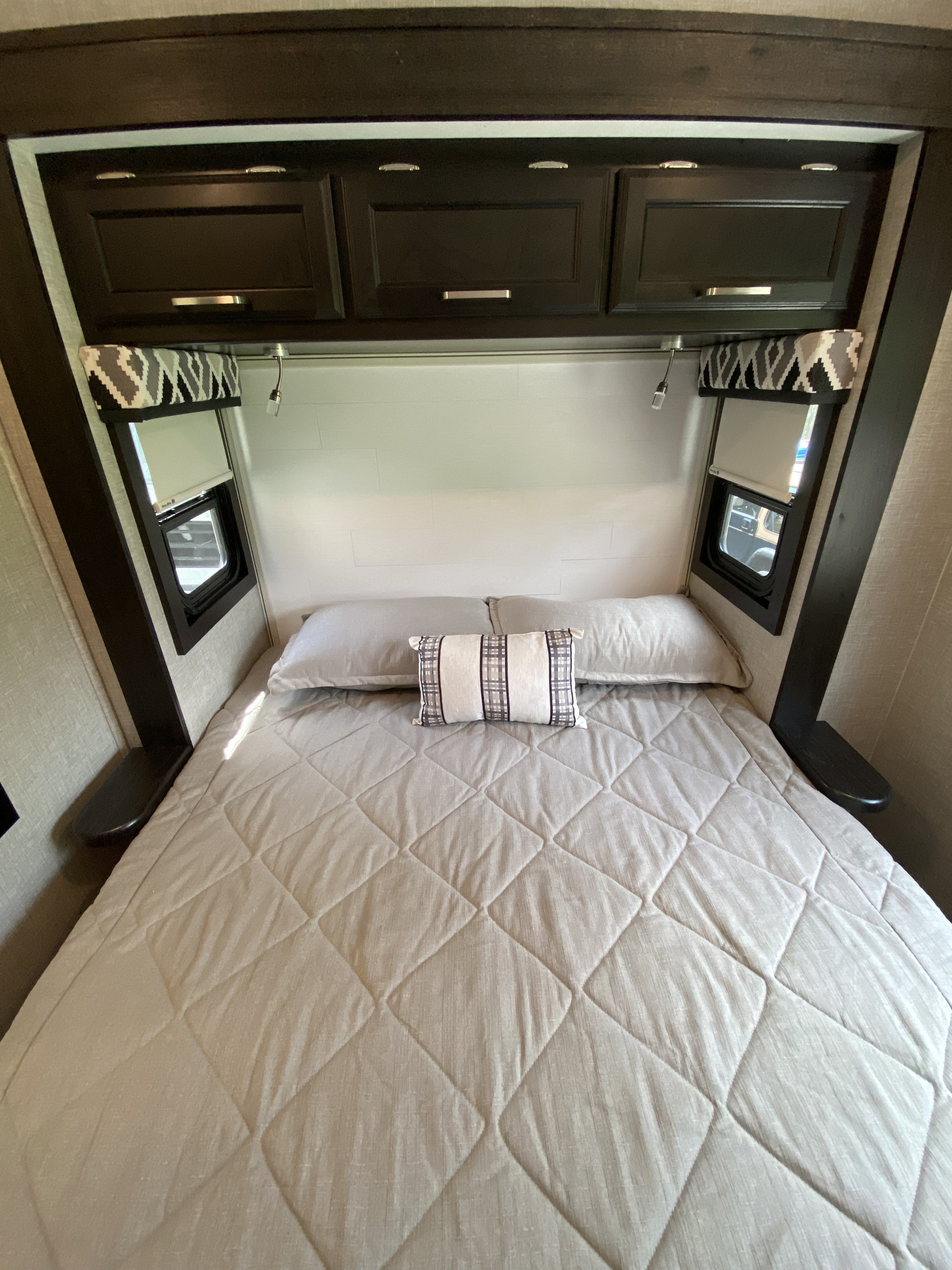 RV rental bedroom: a comfortable sleeping area with quilted bed, overhead cabinets, and side windows for your travels.. Jayco Other 2022