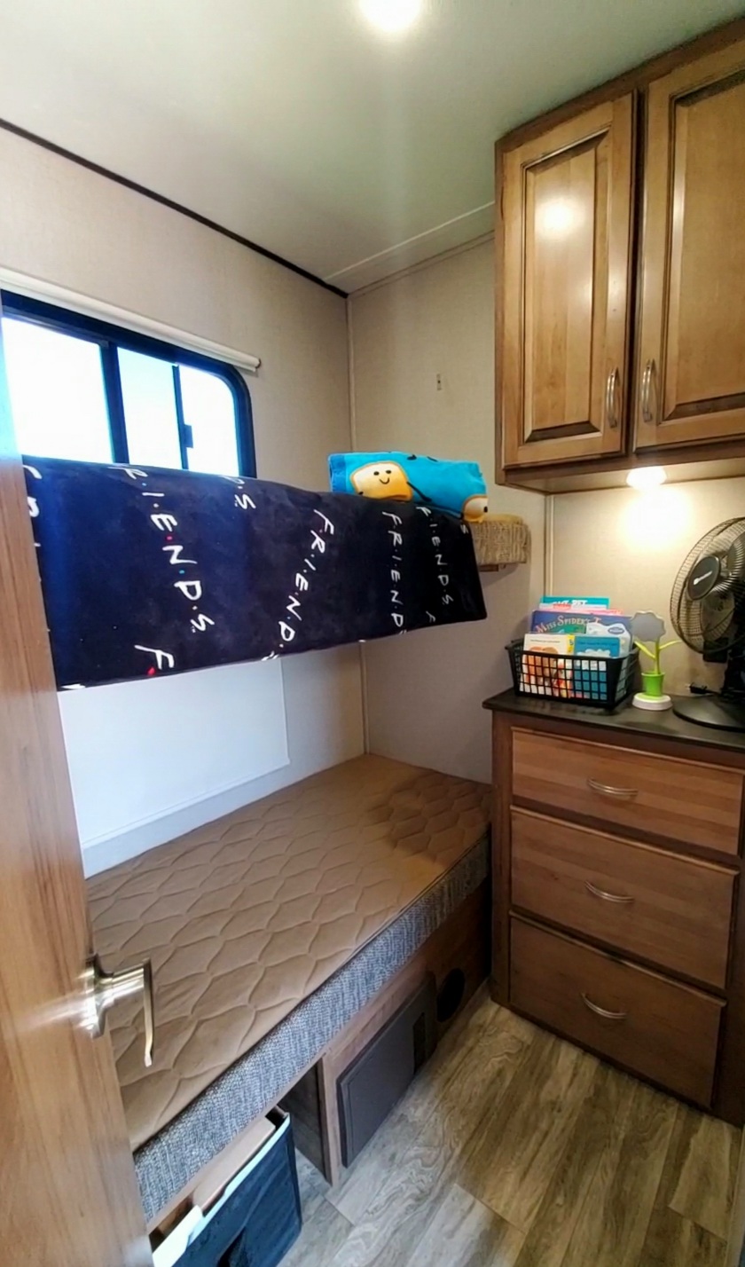 RV rental interior: bunk beds with a 'FRIENDS' blanket, smart storage, and fan create a comfy sleeping space.. Forest River Coachmen Chaparral Lite 2020