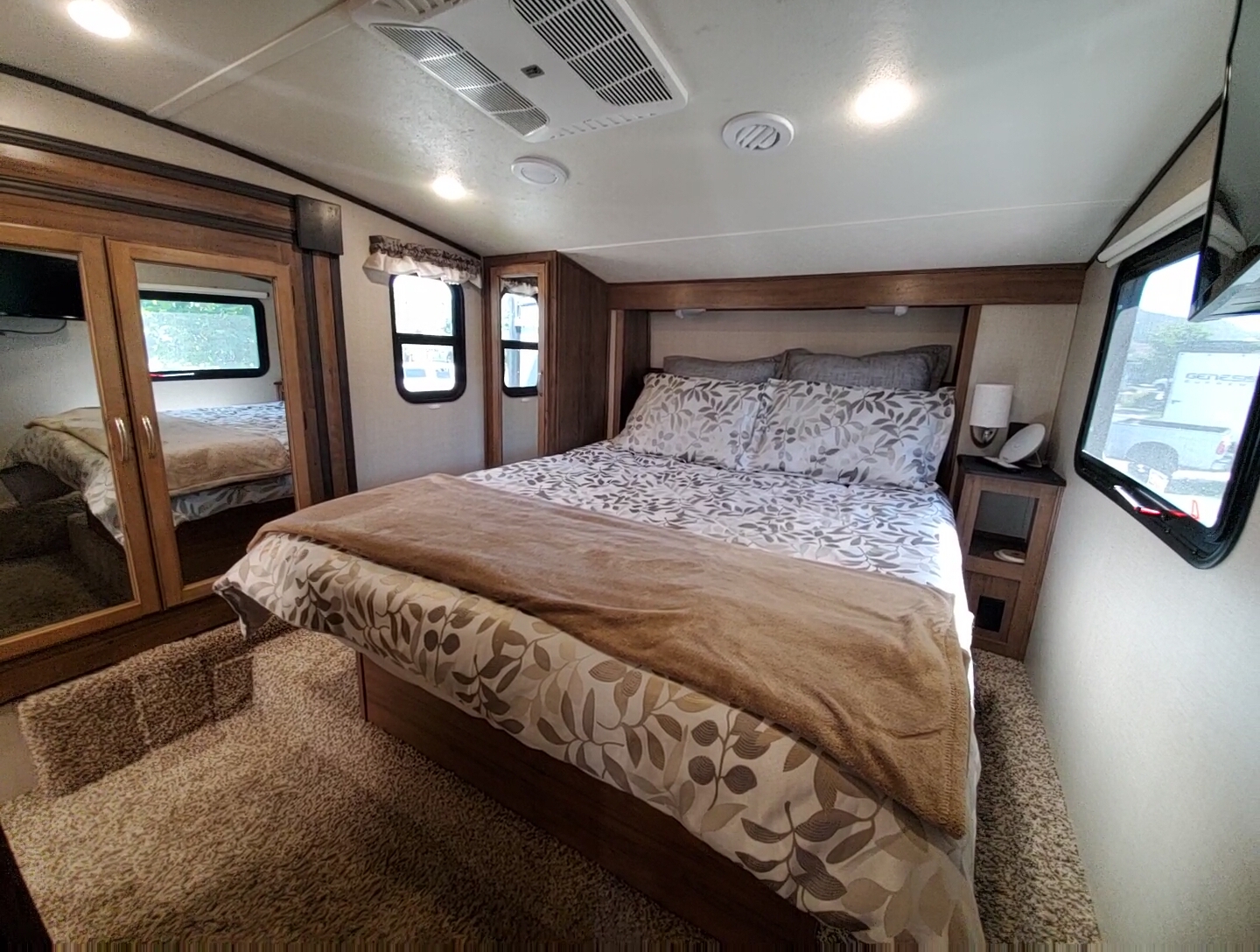 RV rental: Bedroom with a large bed, patterned comforter, mirrored closet, nightstand, and windows. RV interior.. Forest River Coachmen Chaparral Lite 2020