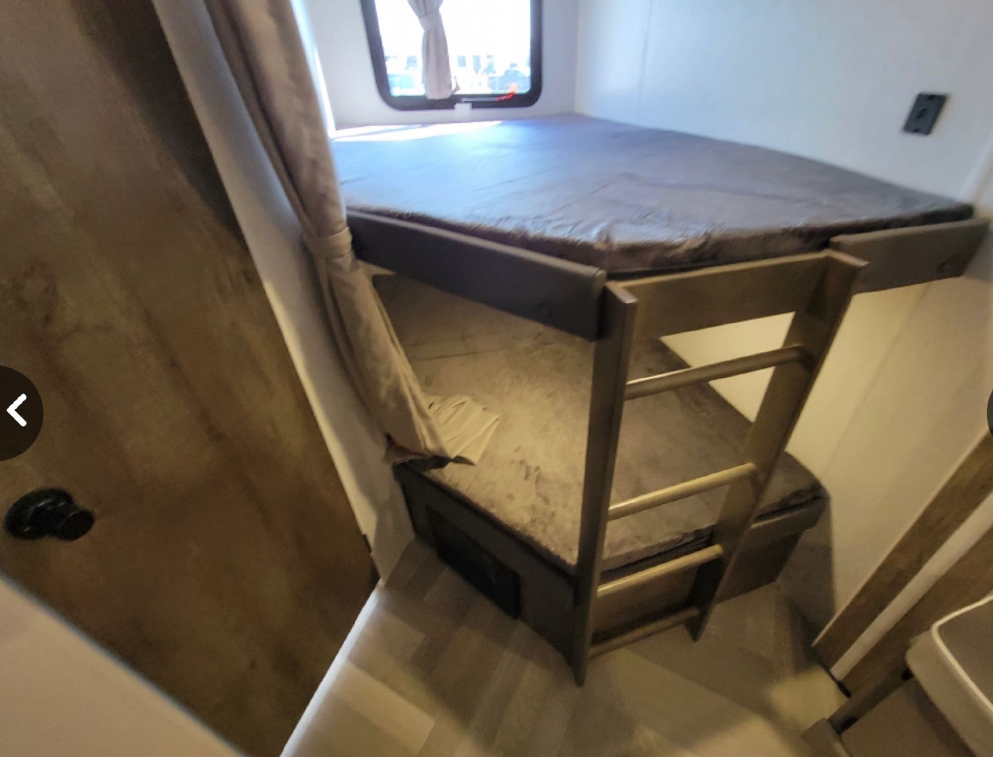 Explore this RV rental's cozy interior, showcasing space-saving bunk beds with a ladder & window, perfect for your next adventure.. Forest River Wildwood X-Lite 2022