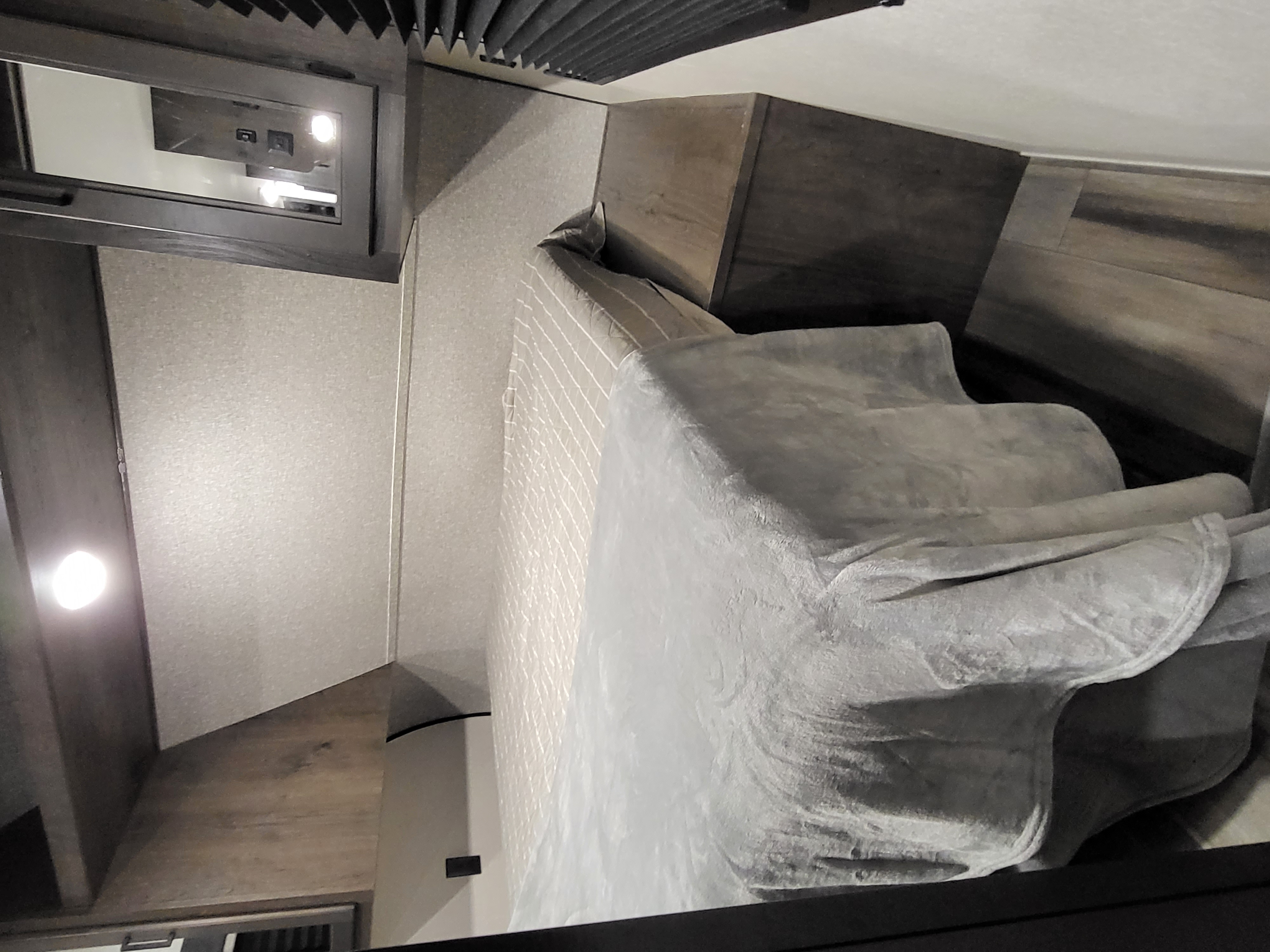 Cozy RV rental bedroom. Features a comfortable bed, smart overhead panel, and ample wood-look cabinetry.. Starcraft Autumn Ridge 2022