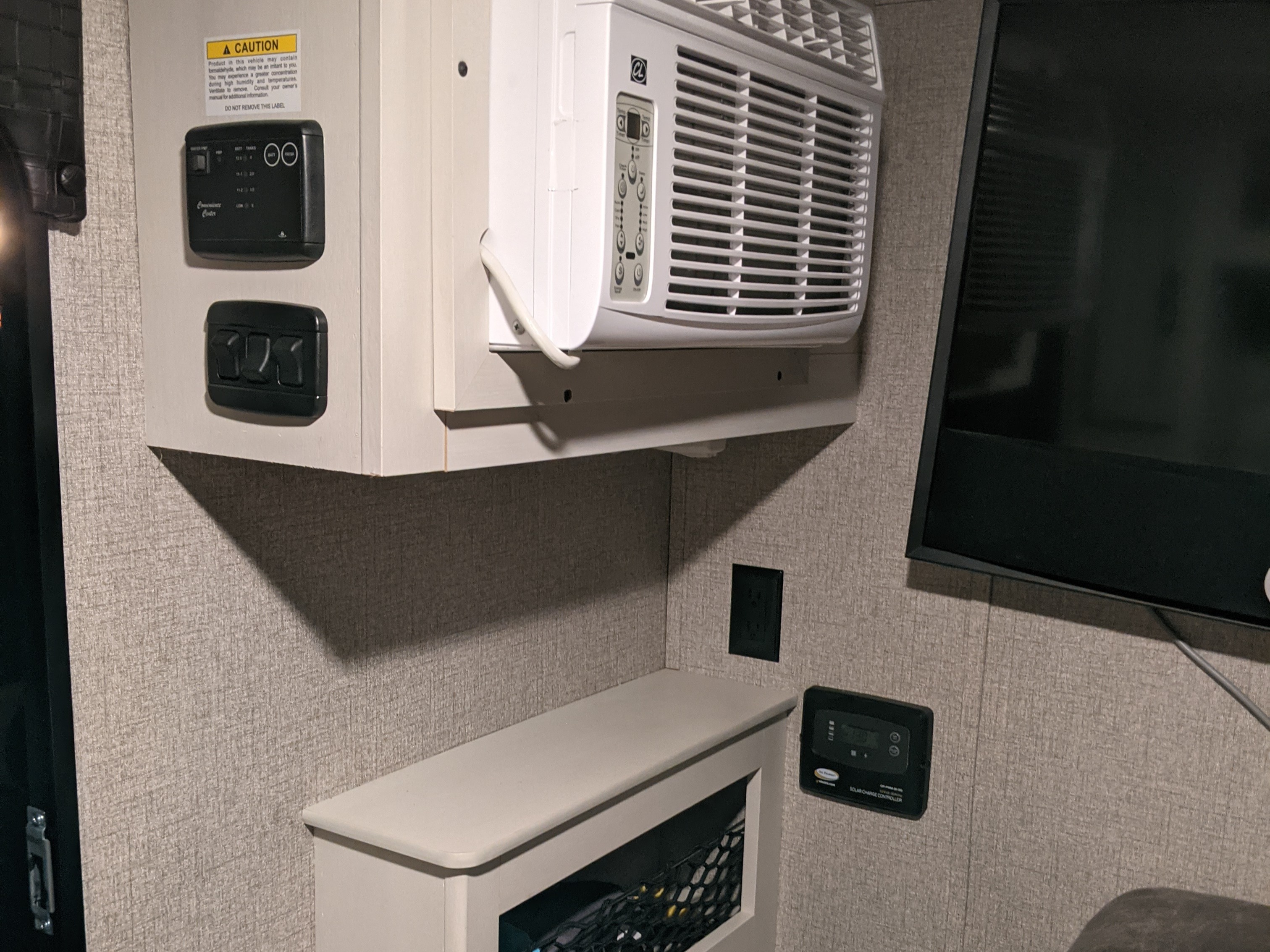 An RV rental's interior, featuring its AC unit, control panels (including solar), and TV setup.. Jayco Jay Feather Micro 12SRK 2021