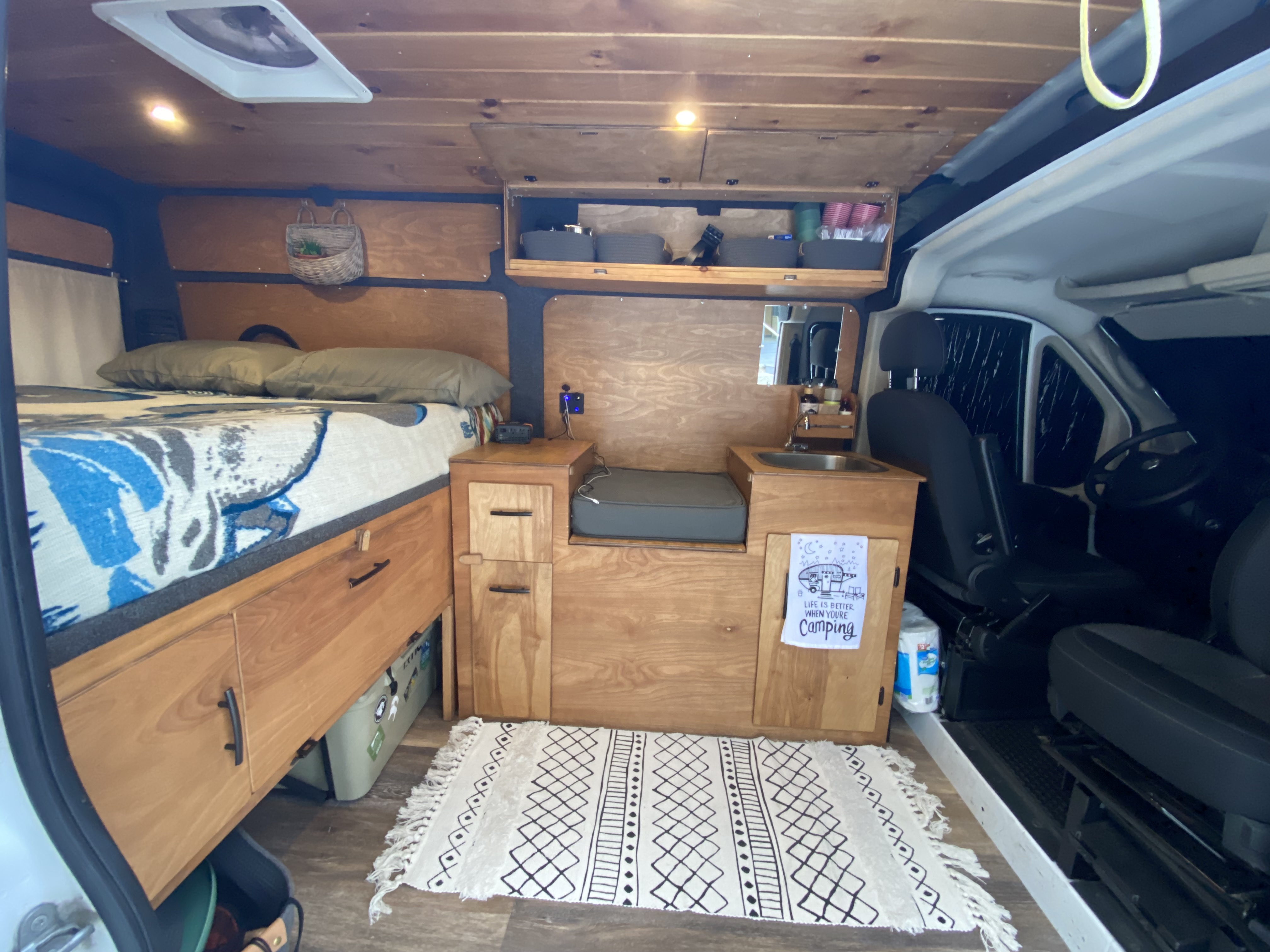Cozy rv rental camper van interior: comfortable bed, functional sink area, and smart storage solutions for your adventure.. Dodge 1500 2017