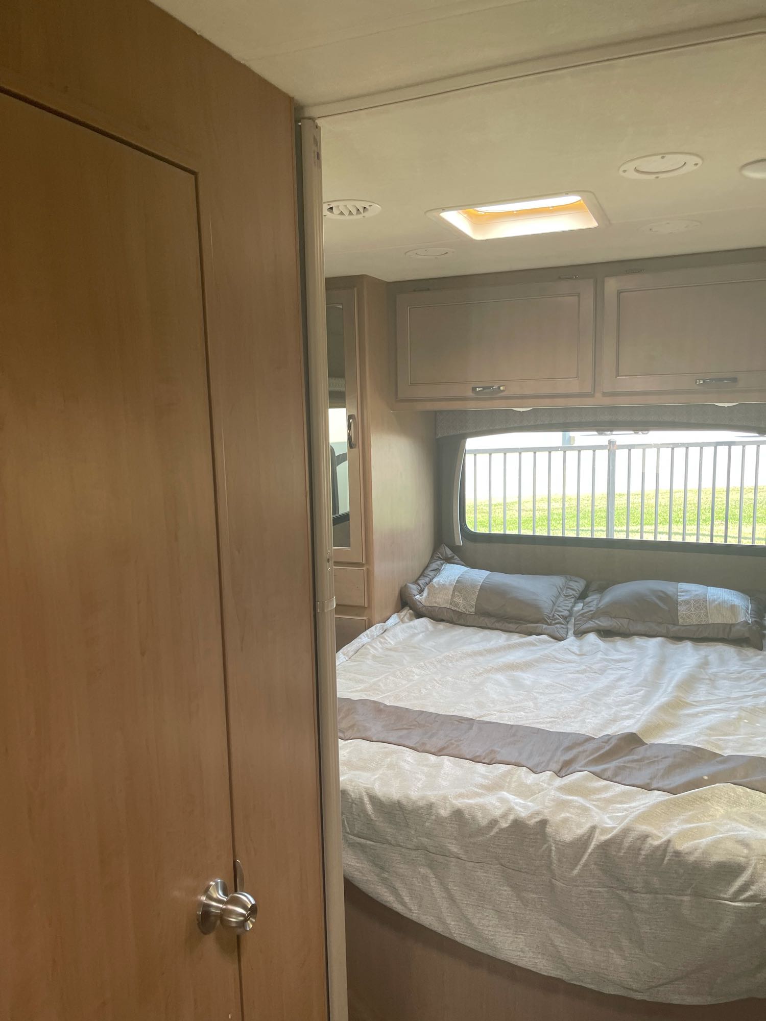 RV rental bedroom interior: comfortable bed, window with outdoor view, and ample overhead storage.. Thor Motor Coach Four Winds 2021