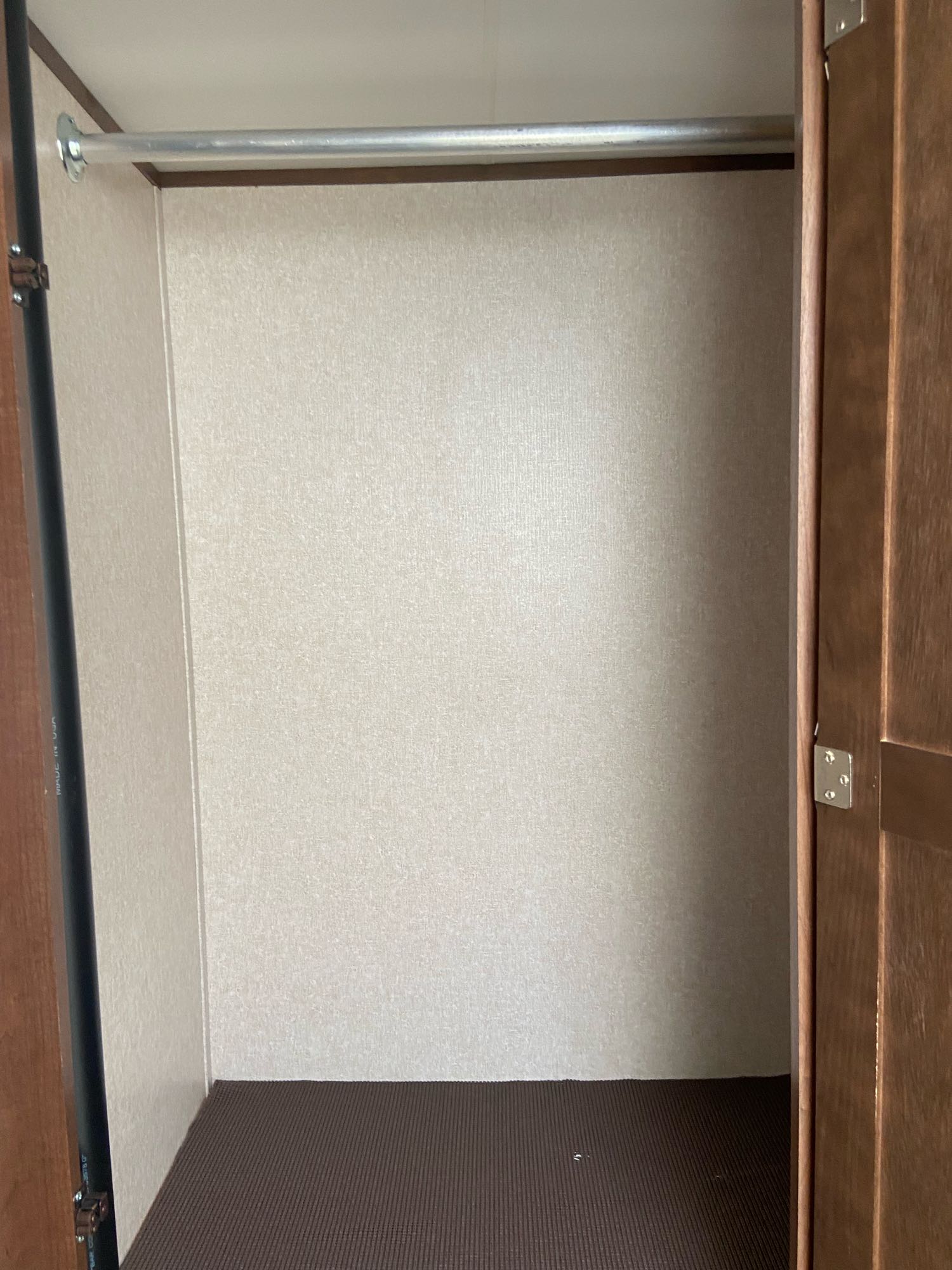 Empty RV rental wardrobe, ready for your clothes. Features a silver hanging rod, light walls, and textured brown floor.. Jayco Jay Flight 2017