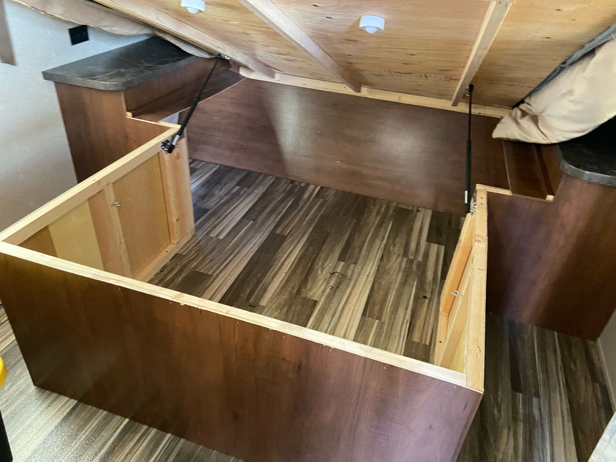 RV rental interior: lifted bed reveals under-bed storage, showing gas struts and wood-look floor. Great for packing!. Jayco Jay Flight 2017