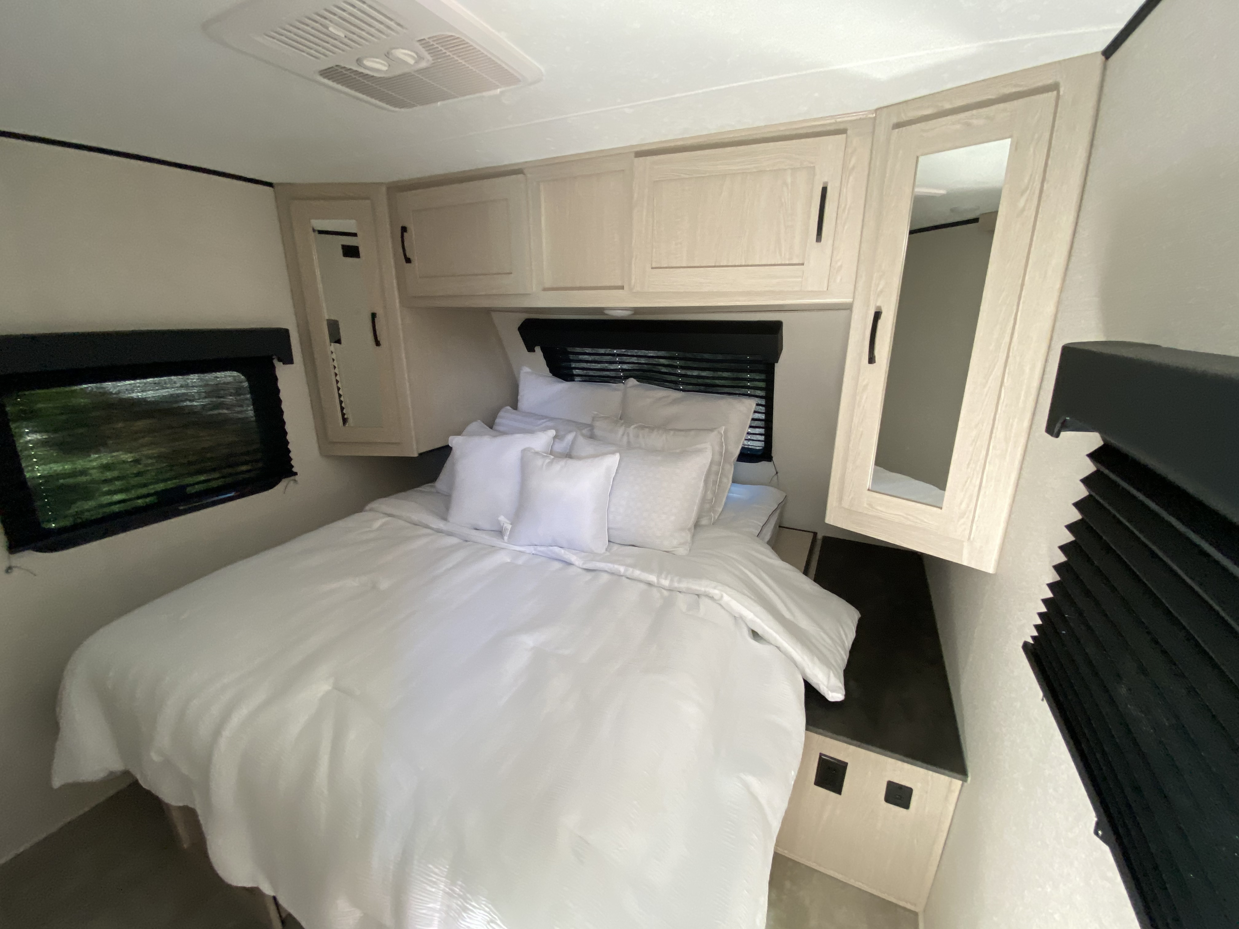 This clean, cozy RV rental bedroom features a comfy white bed, overhead storage, and side windows.. Coachmen Other 2021