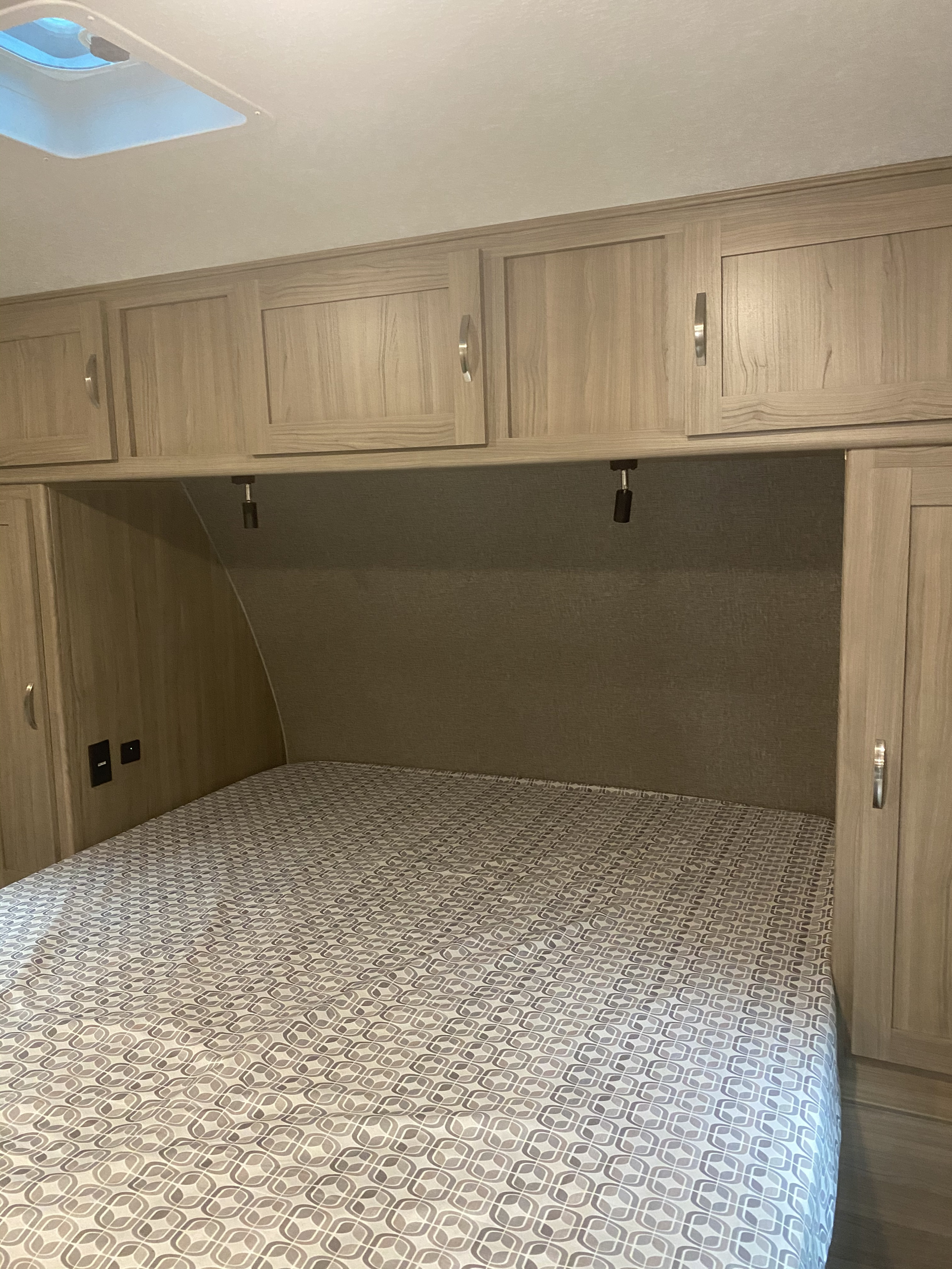 RV rental bedroom: a comfy bed, overhead storage, side charging ports, and a ceiling vent for natural light.. Coachmen Adrenaline 2021