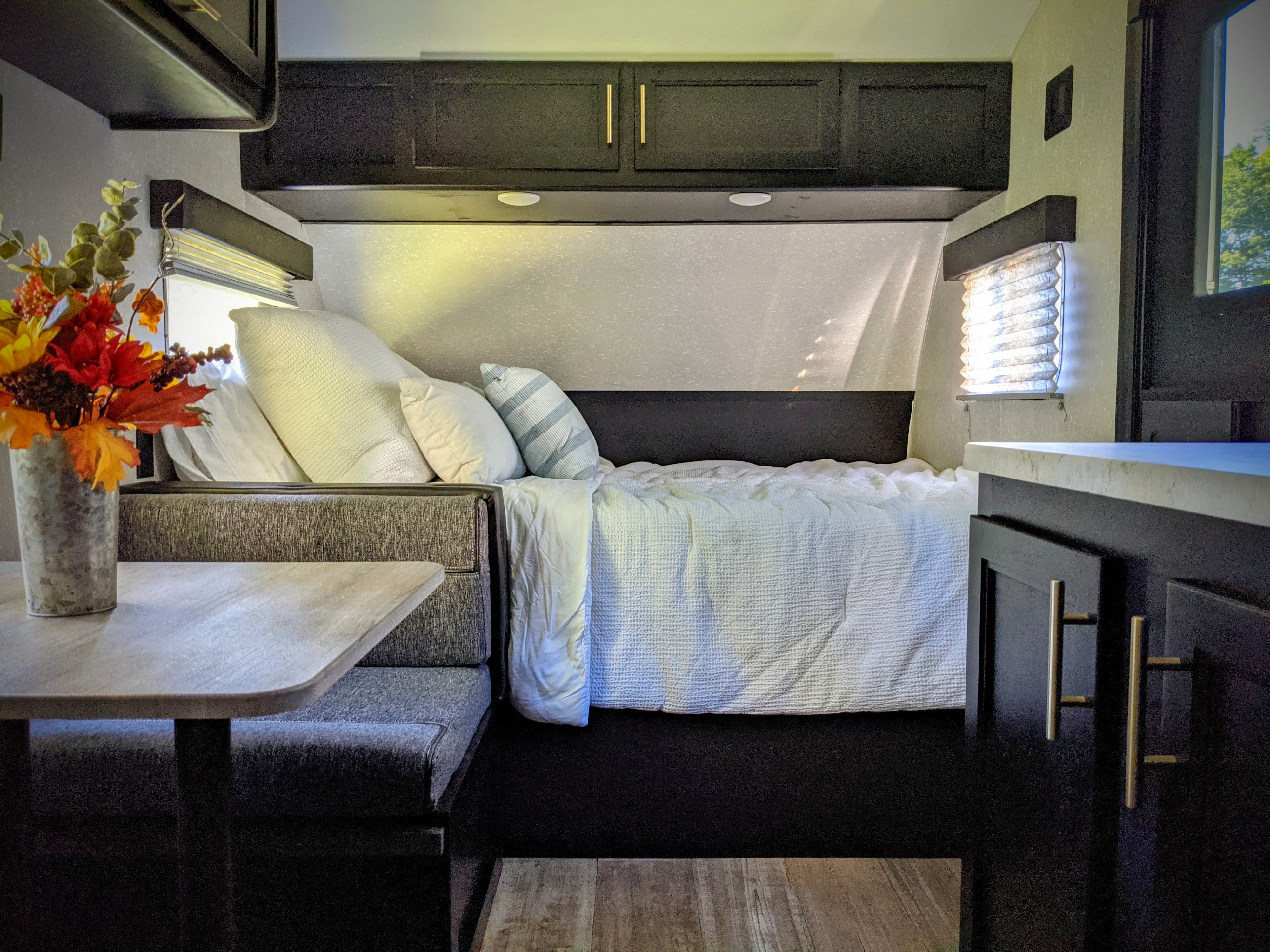Cozy RV rental interior with a bed, sleek dark cabinets, and a dining area on the left, ready for adventure.. Forest River Cherokee Wolf Pup 2021