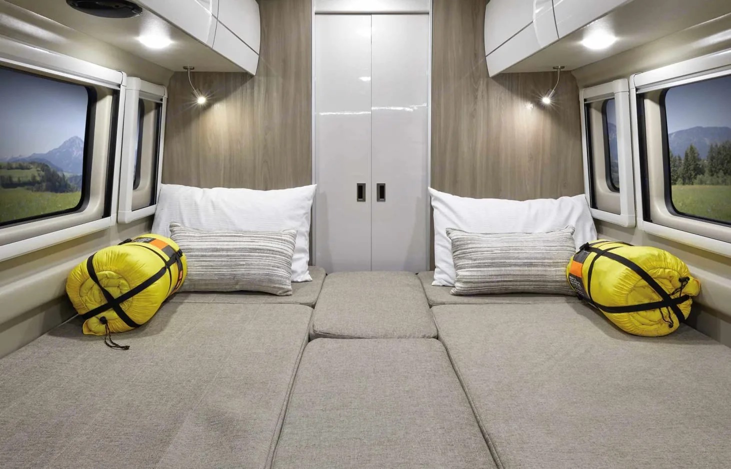 Comfortable rv rental interior with twin beds, bright yellow sleeping bags, and scenic mountain views from windows.. Thor Sequence 2021