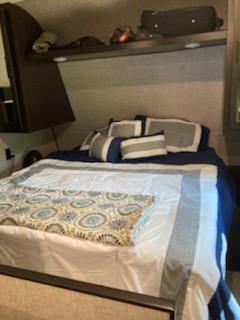 Experience comfort in this RV rental bedroom: a spacious bed with blue and white linens, overhead storage, ready for adventure.. Jayco Jay Flight 2022