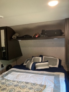Inside an RV rental: a compact bedroom with a comfortable bed, pillows, and convenient overhead storage shelf.. Jayco Jay Flight 2022