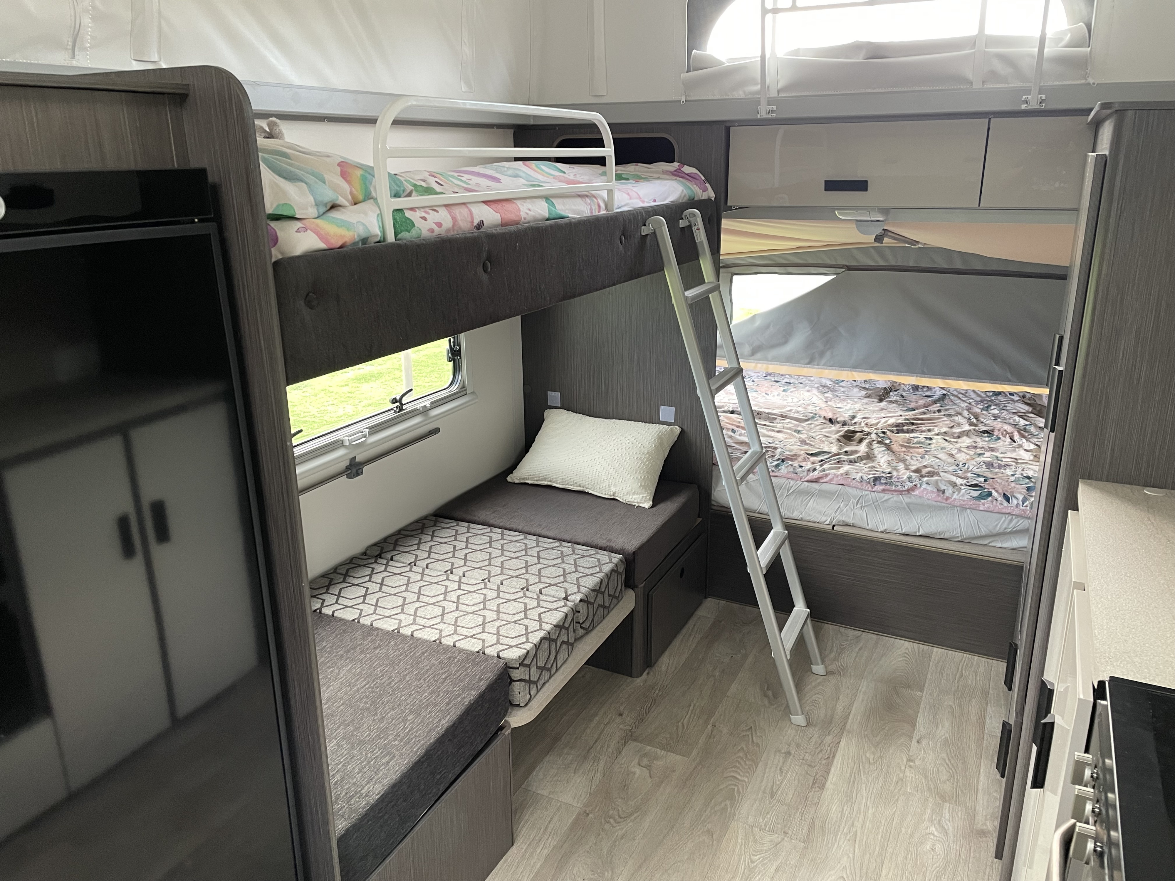 Spacious RV rental interior featuring comfortable bunk beds, a ladder, window view, and ample storage for a cozy camper experience.. Jayco Expanda 17.56 Outback 2021