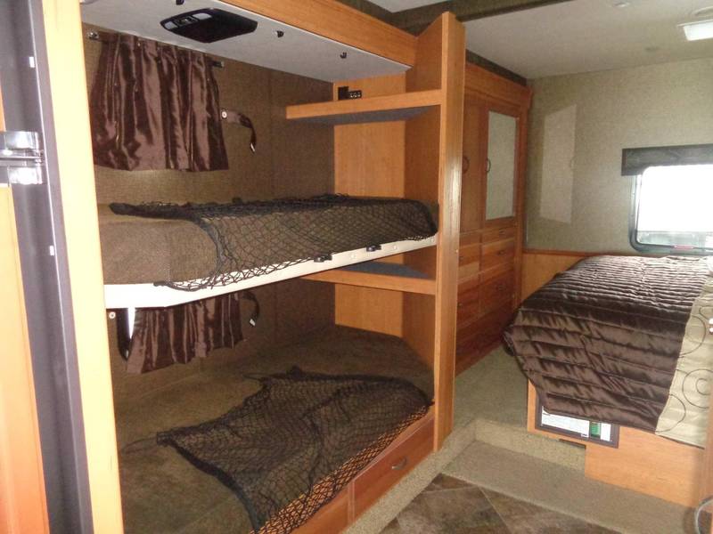Well-equipped rv rental interior features bunk beds with safety nets, a main bed, and storage. Great for families!. Holiday Rambler Admiral 2016