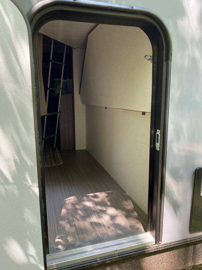 Step inside an RV rental! View of the interior showing a bunk bed ladder, an open storage area, and wood-look flooring.. Other Passport 2020