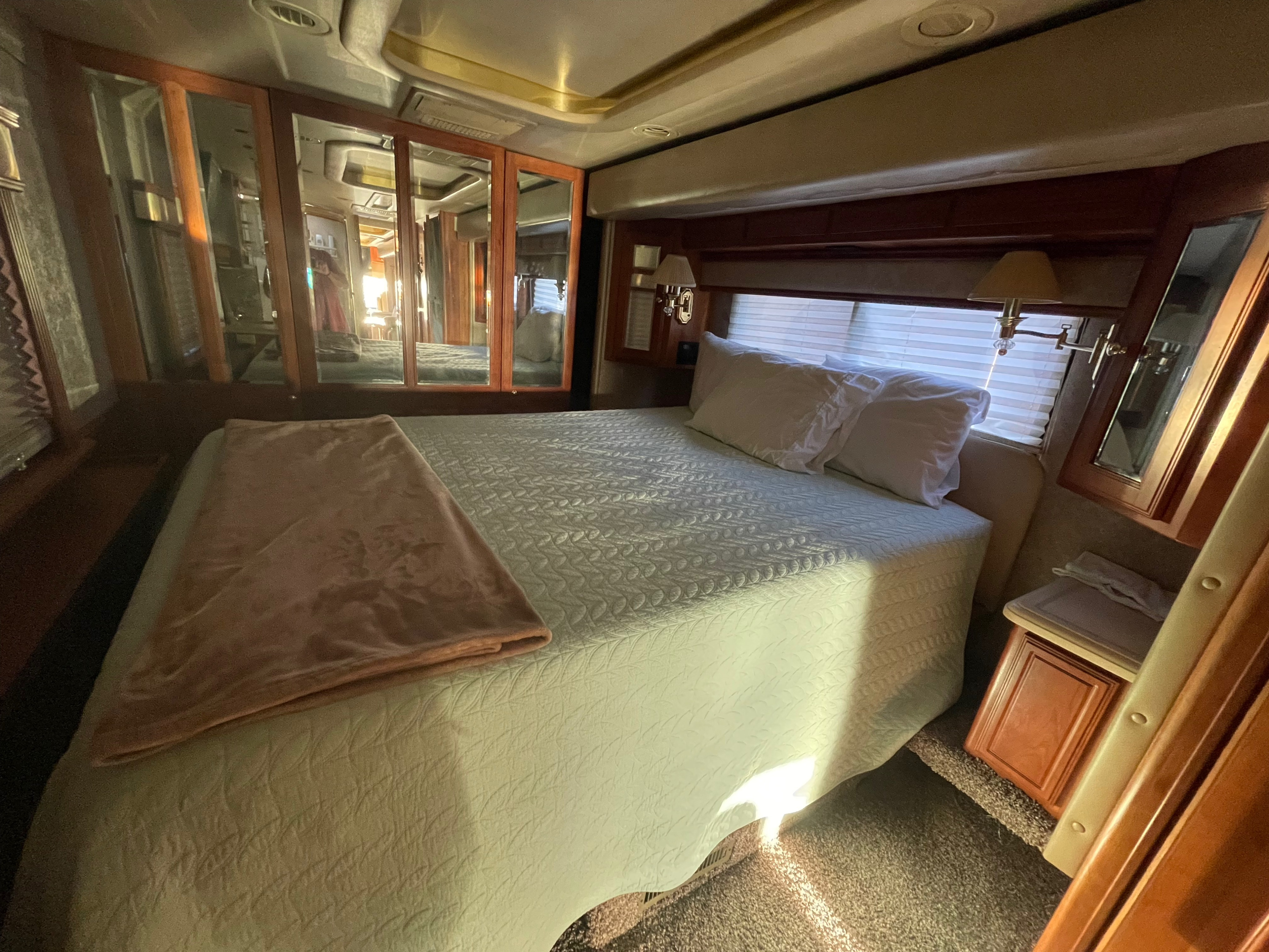 Comfortable RV rental bedroom with a large bed, mirrored cabinets, and ample natural light. Perfect for travel comfort.. Foretravel U-320 2001
