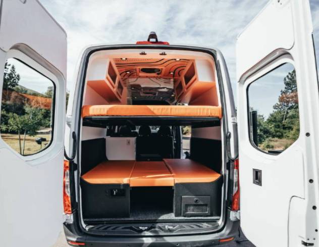 Inside a modern RV rental: view of the camper van's custom interior with a versatile bunk bed system and orange cushions.. Mercedes-Benz Sprinter 2020