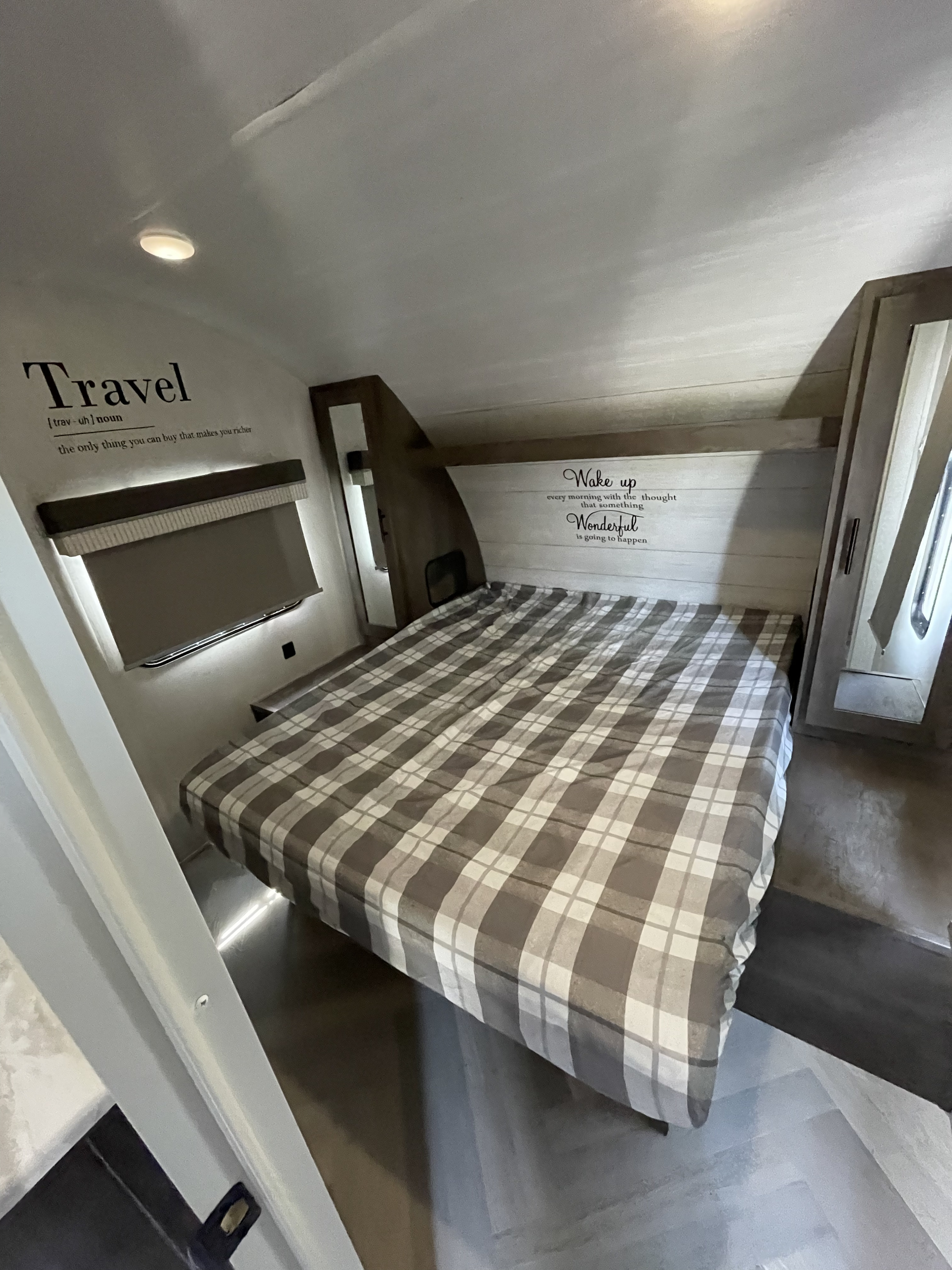Cozy RV rental bedroom with plaid bedding and inspirational wall decor, perfect for travel adventures.. Forest River Wildwood X-Lite 2021