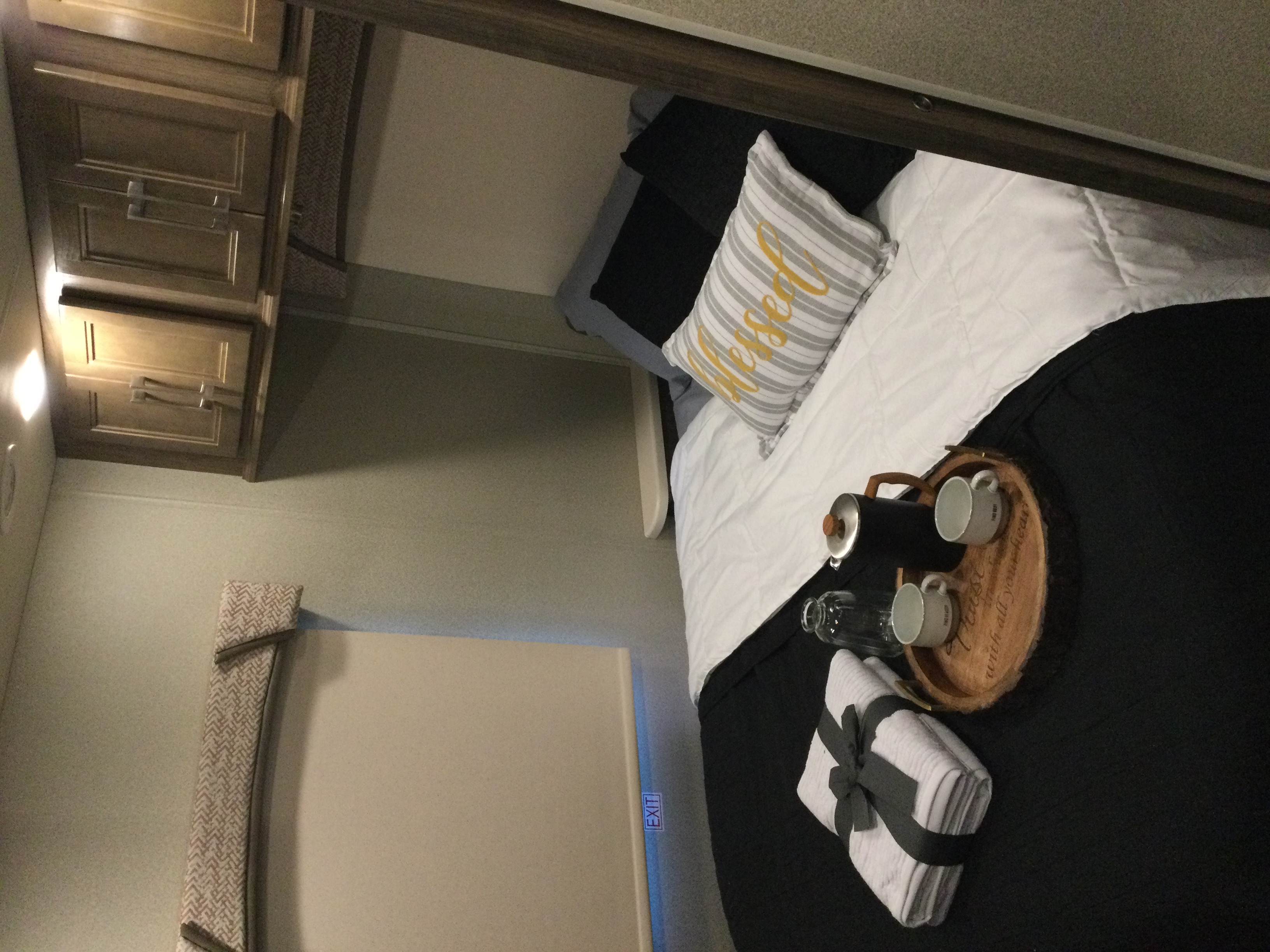 Cozy RV rental bedroom: bed with "Blessed" pillow, coffee tray, and neatly folded towels for a comfortable stay.. Jayco Greyhawk 2018