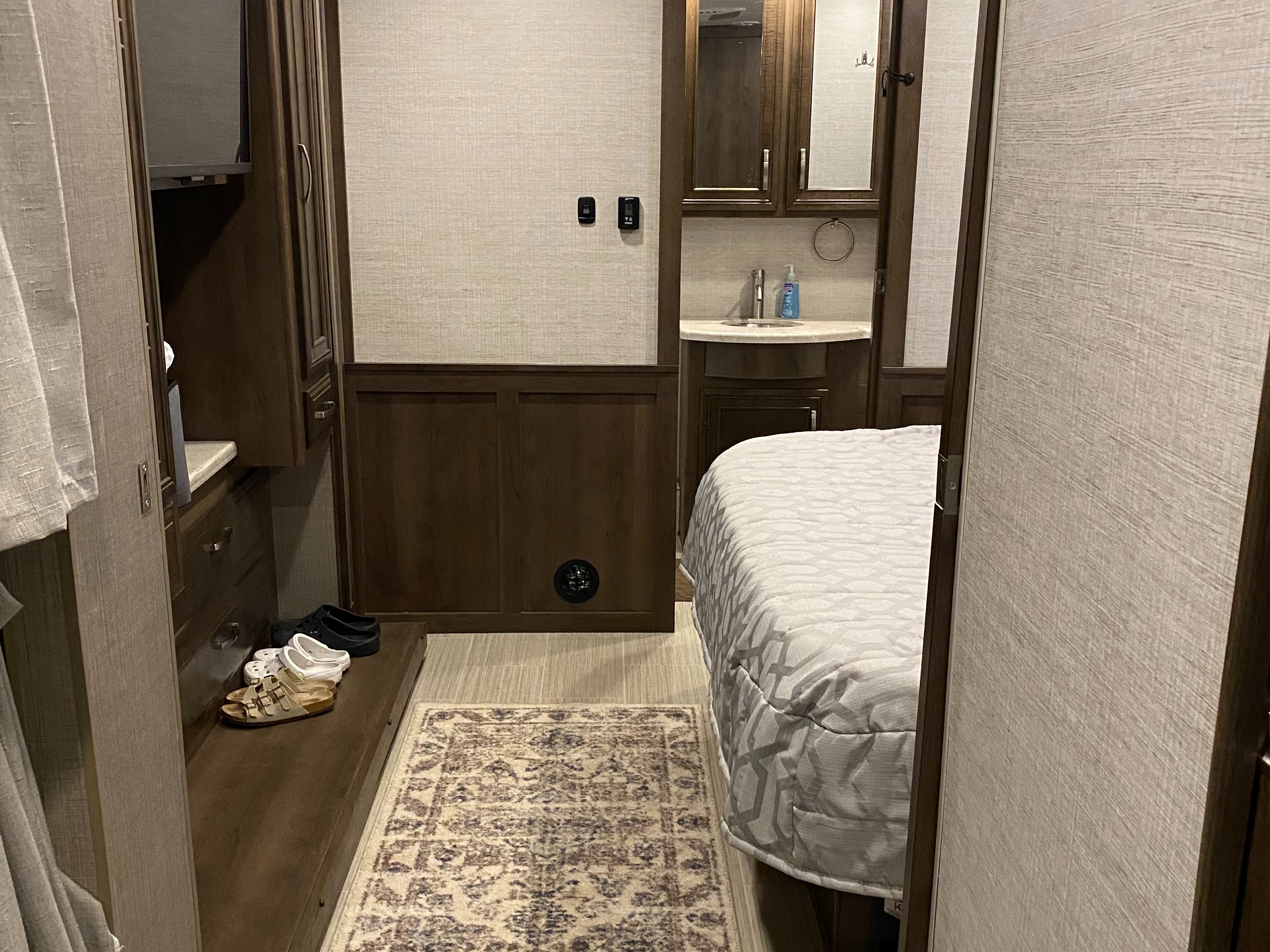 Cozy RV rental interior showcasing a bed, compact bathroom vanity with a sink, and built-in storage.. Entegra Coach Vision XL 2021