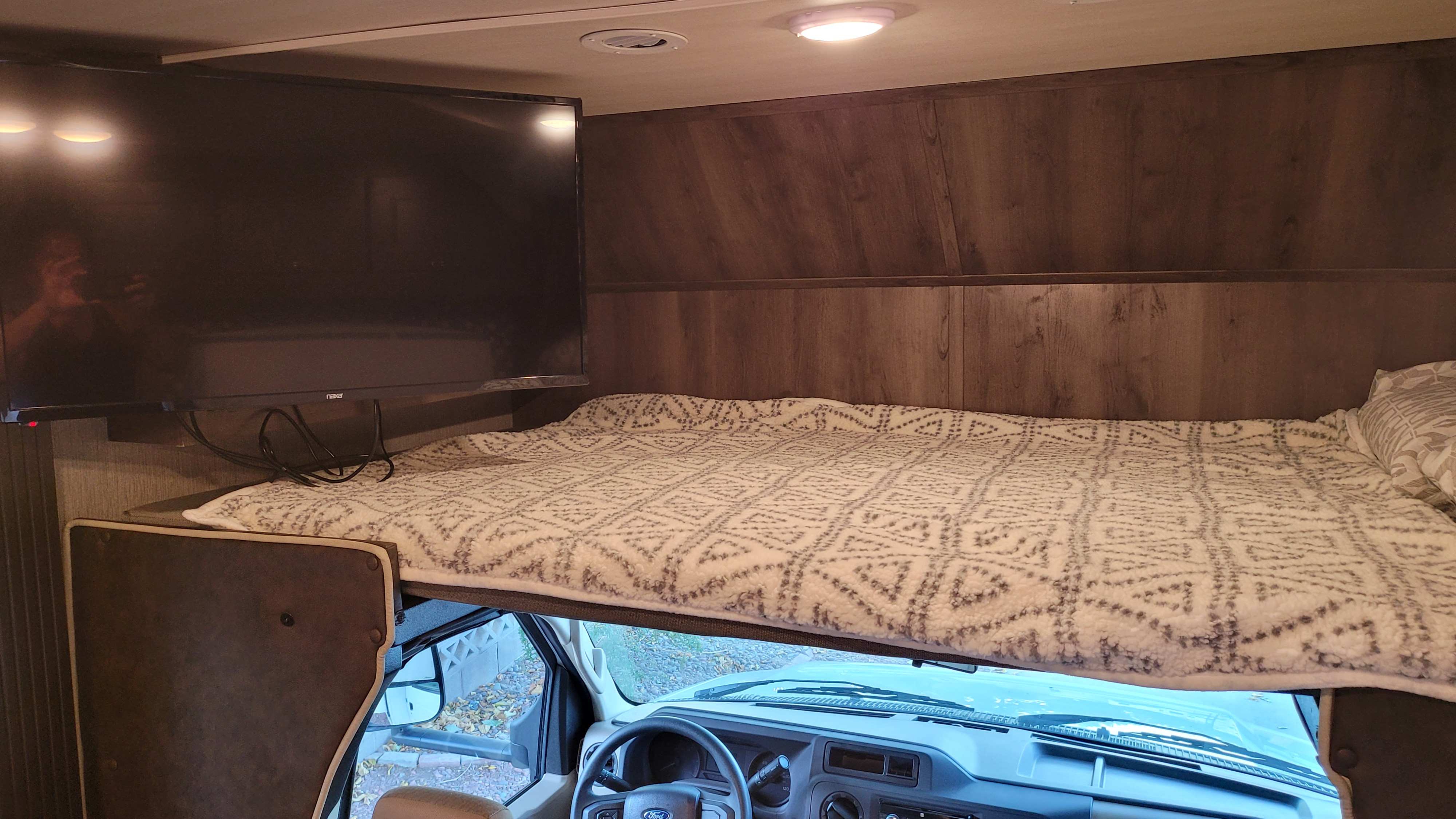 Spacious RV rental cab-over bunk features a comfy bed, TV, and cab view below. Ready for your next adventure!. Other Other 2022