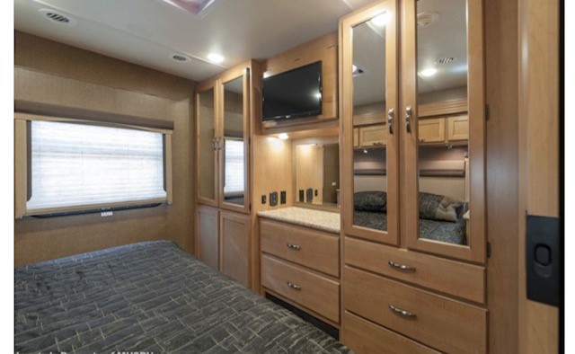 Bright RV rental bedroom: bed, window, TV, light wood cabinetry with dresser & mirrored closets. Plenty of storage for your travels.. Thor A.C.E. 2016