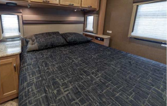 RV rental bedroom: Relax in this cozy space with dark patterned bedding, overhead cabinets, and bedside windows.. Thor A.C.E. 2016
