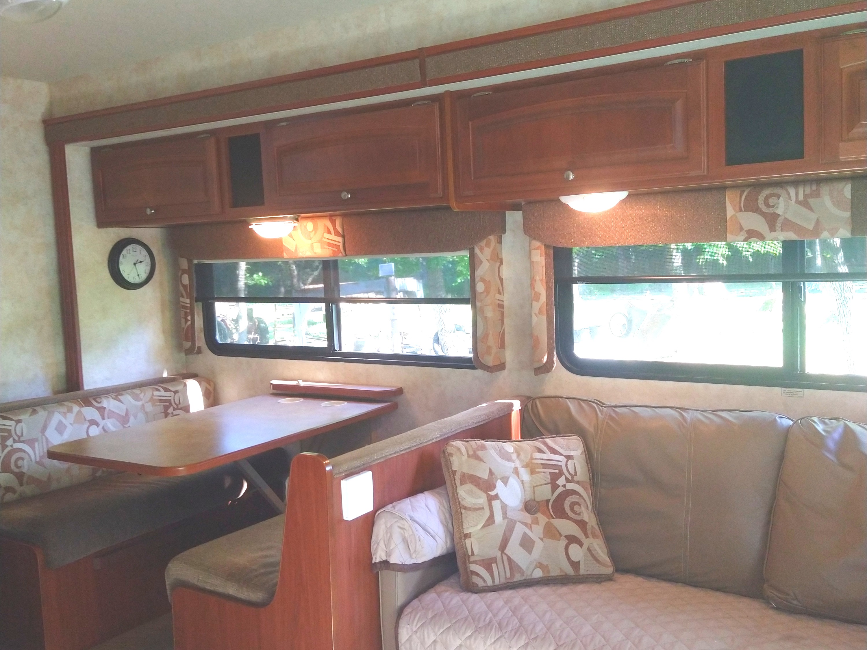 Cozy RV rental interior with a dinette, sofa, and overhead cabinets, offering comfort for travel.. Winnebago Access 2011