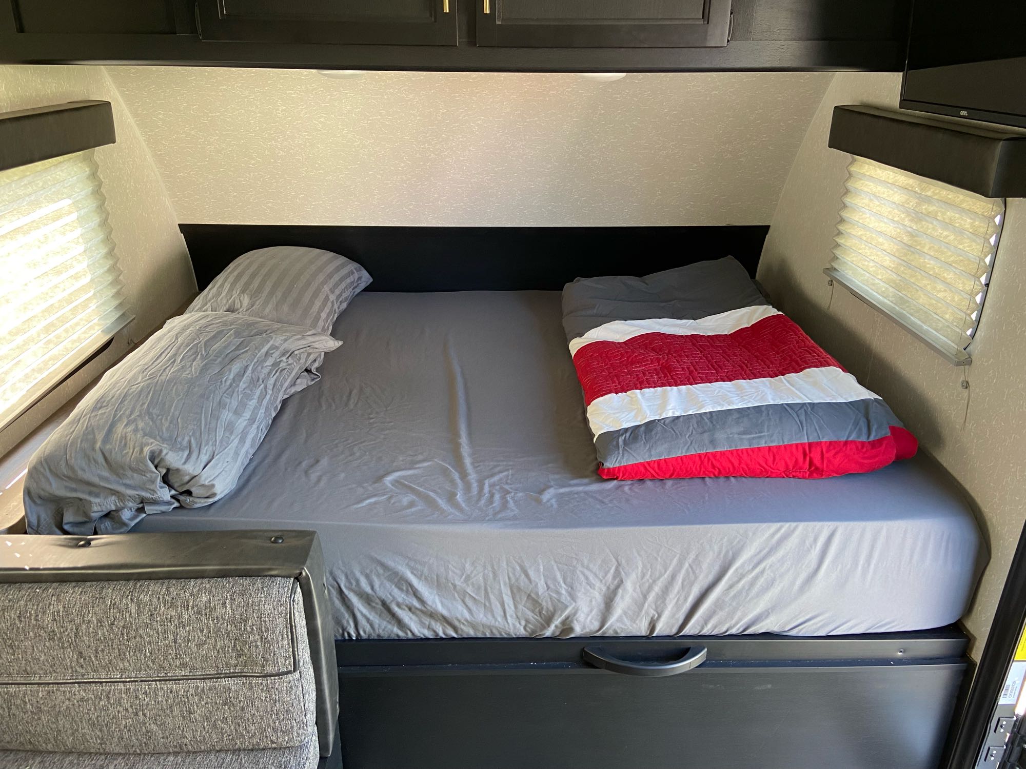 RV rental interior: A comfortable sleeping area with a bed, grey sheets, pillows, and a red & white comforter.. Forest River Cherokee Wolf Pup 2021