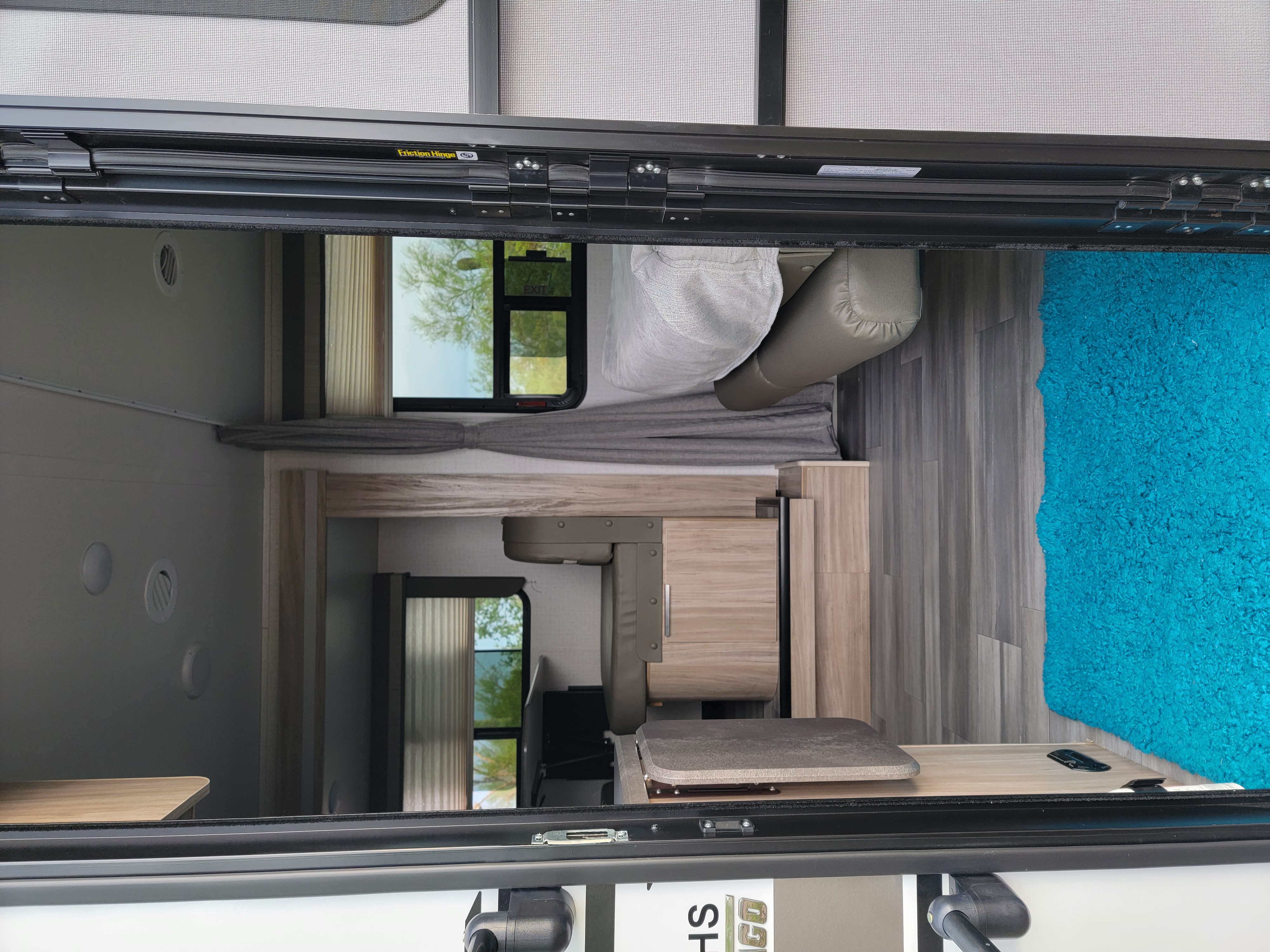 Looking inside a modern RV rental, featuring a compact living area with bed, cabinetry, and contrasting flooring.. Winnebago Micro Minnie 2021
