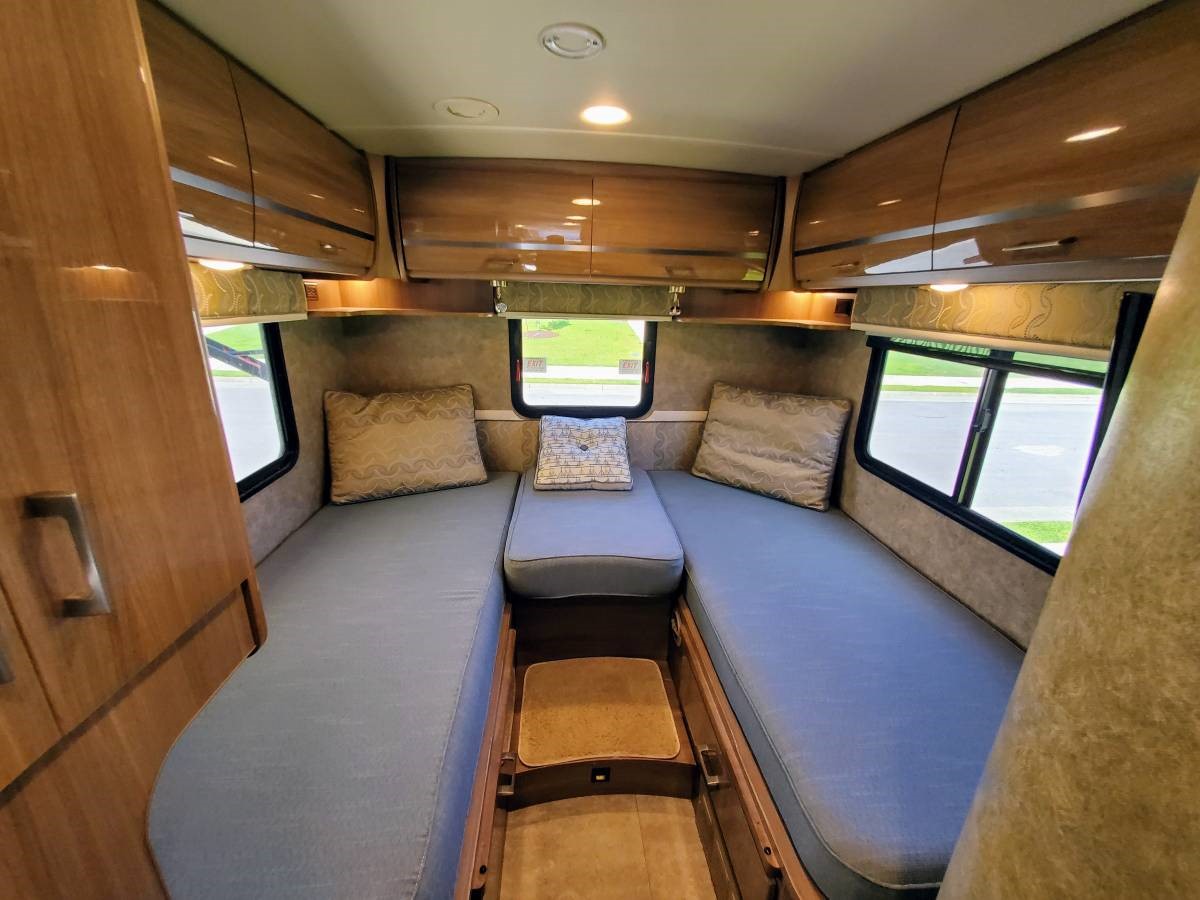 Explore this comfortable RV rental sleeping area featuring twin beds, overhead cabinets, and bright windows.. Winnebago View 2015