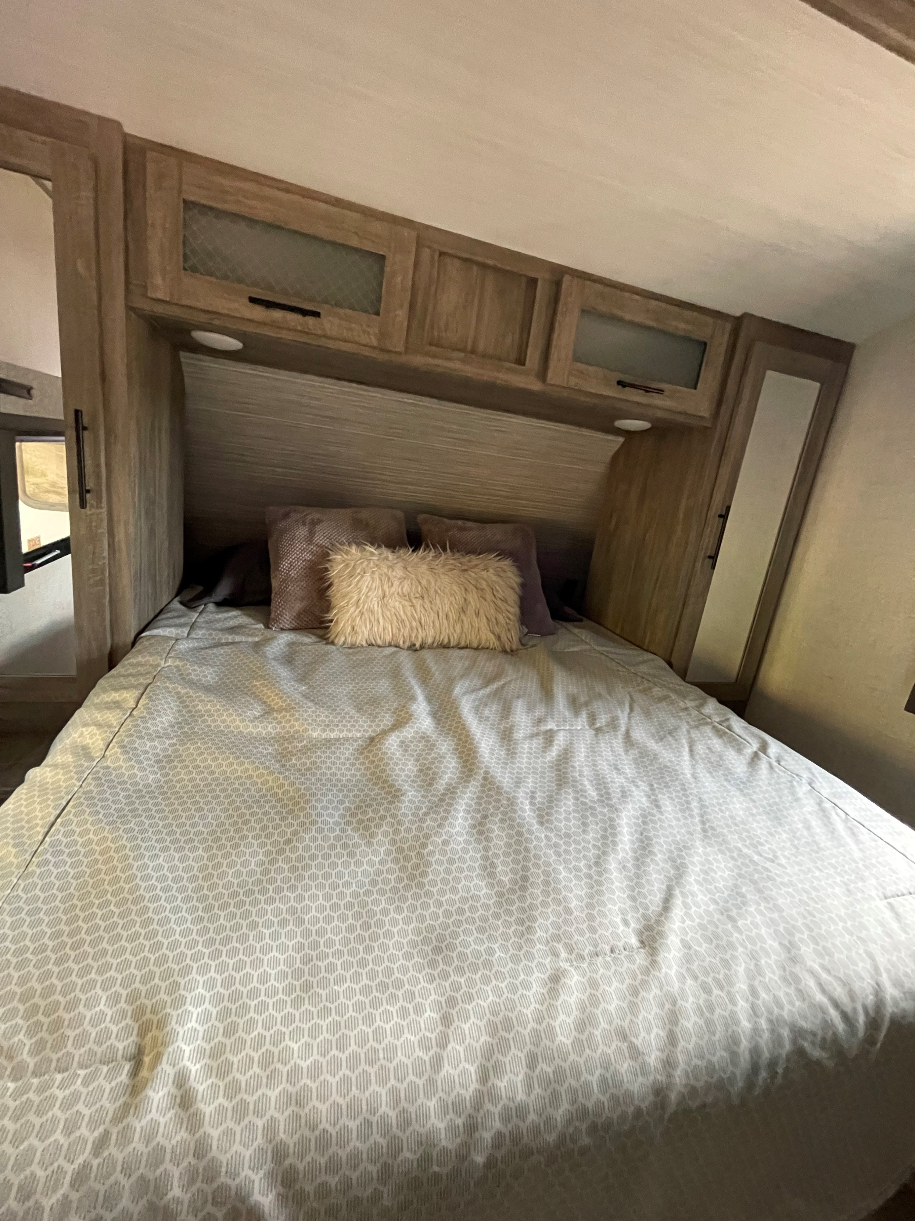Cozy RV rental bedroom featuring hexagonal patterned bedding, functional overhead cabinets, and built-in storage.. Forest River Salem Hemisphere 2021