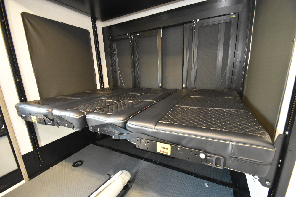 RV interior featuring black quilted, adjustable beds/sofas in a garage area, ready for your next RV rental adventure.. Keystone Raptor 2023