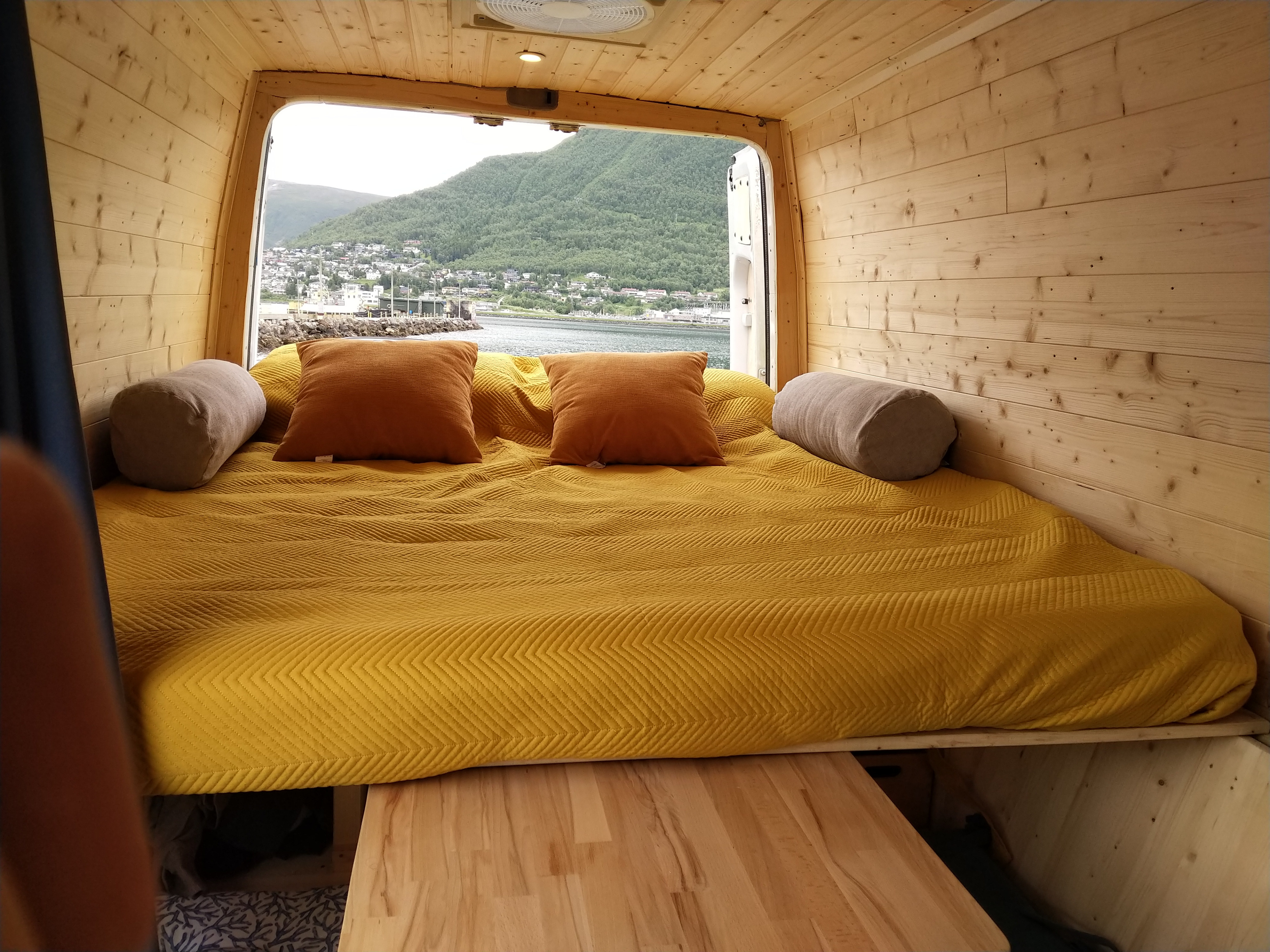 Cozy RV rental bedroom: yellow quilted bed and pillows with panoramic views of a town, water, and mountains.. Mercedes-Benz Sprinter 2008
