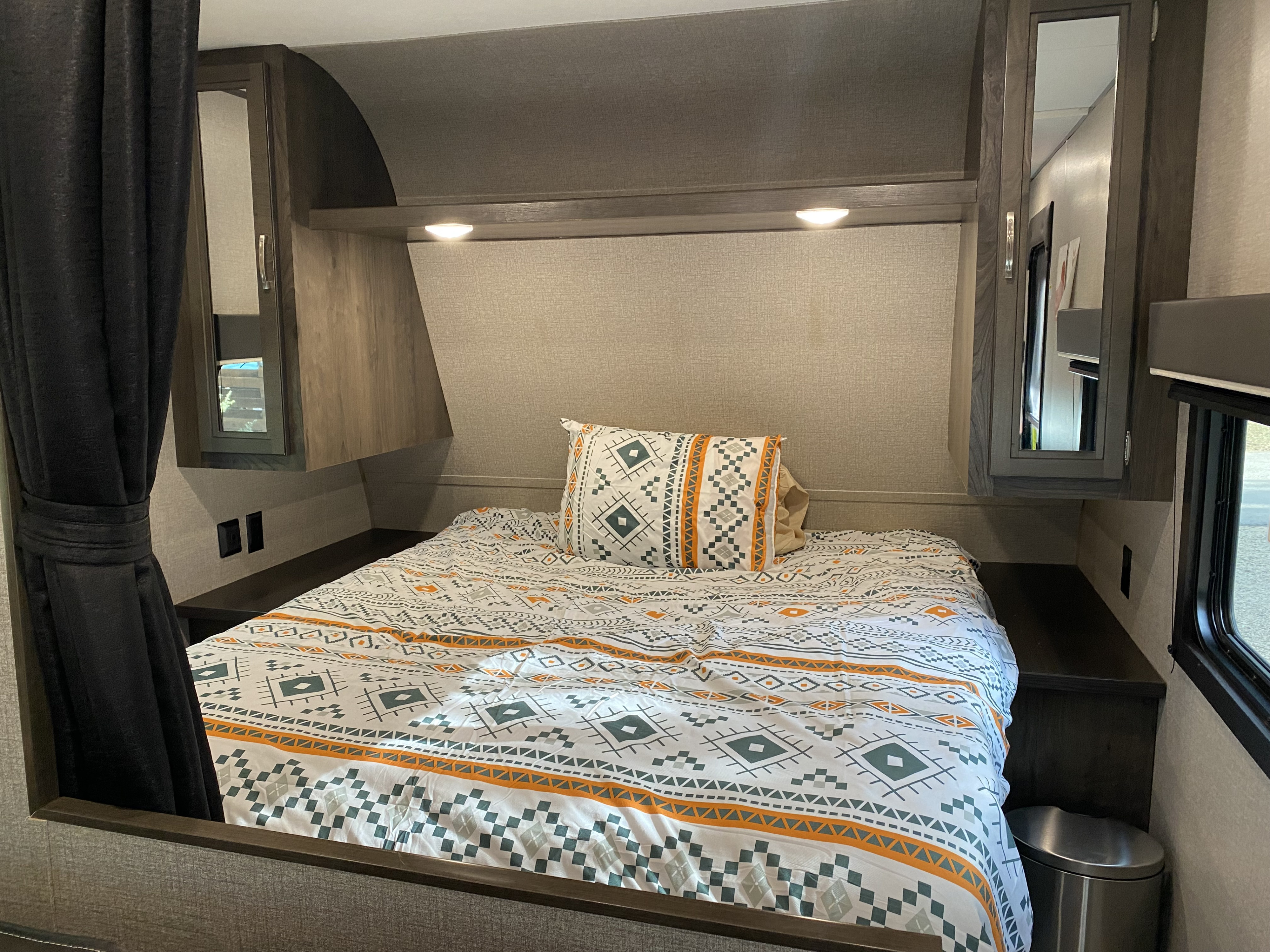 Cozy RV rental bedroom featuring a patterned bed, overhead storage, and ambient lighting, perfect for travel.. Jayco Jay Flight 2020