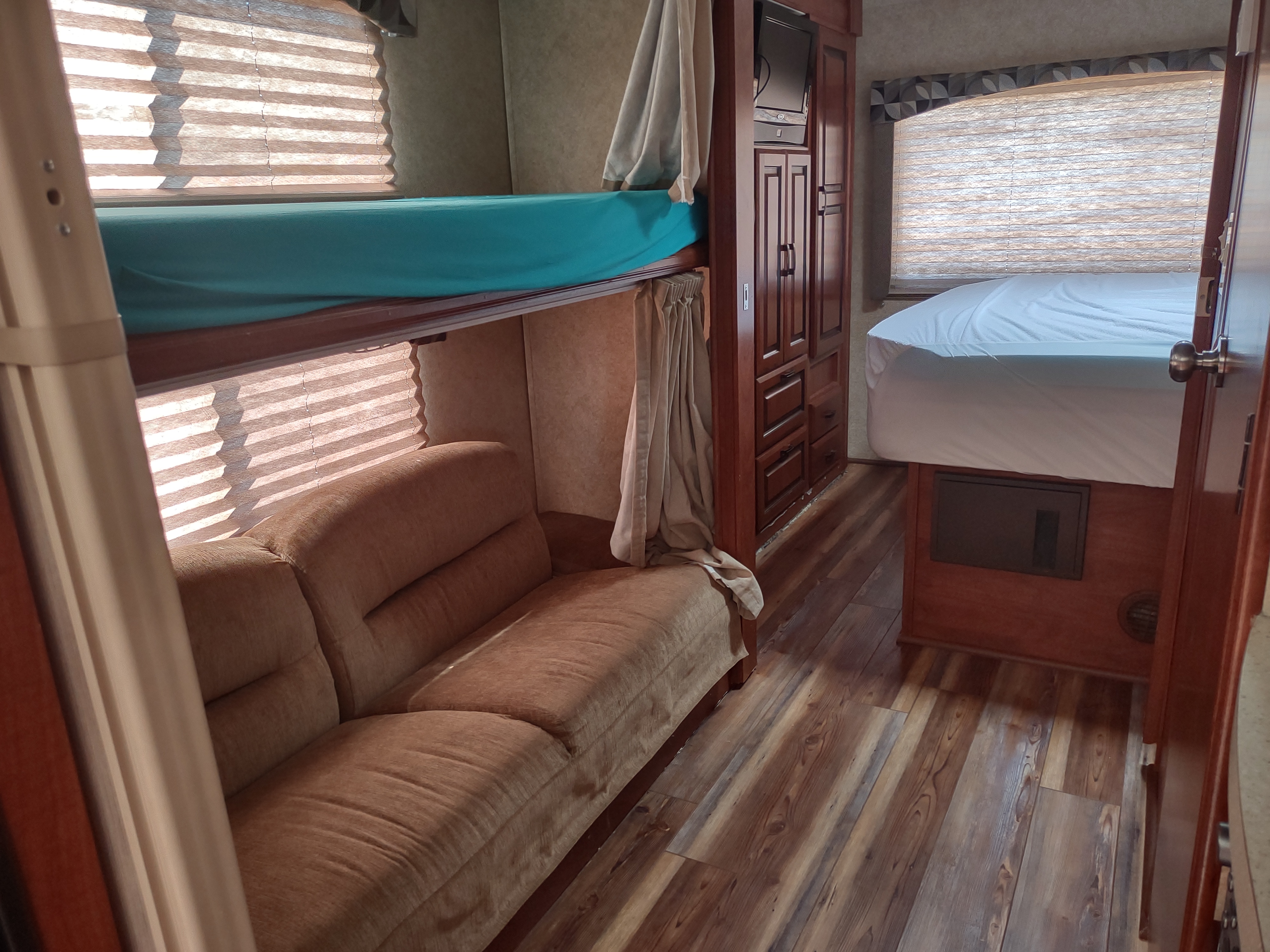 RV rental interior with master bed, bunk beds, sofa, and modern wooden flooring, all bathed in natural light.. Forest River Sunseeker 2012