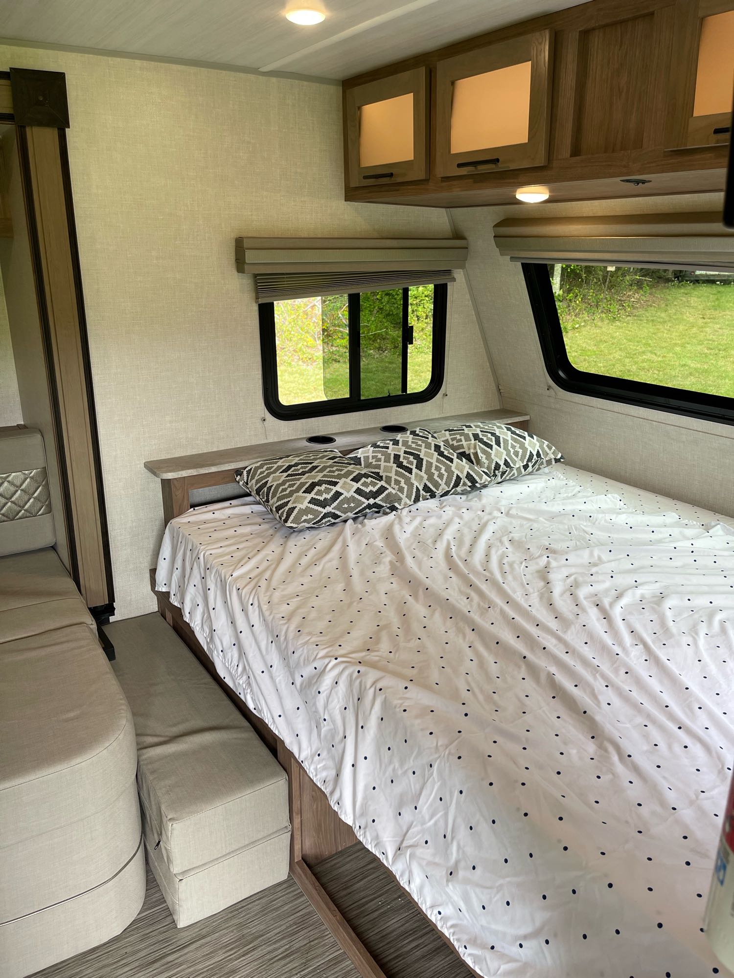 A bright RV rental interior showing a comfortable bed, sofa, and overhead cabinets for a cozy trip.. No Boundaries 19 2021