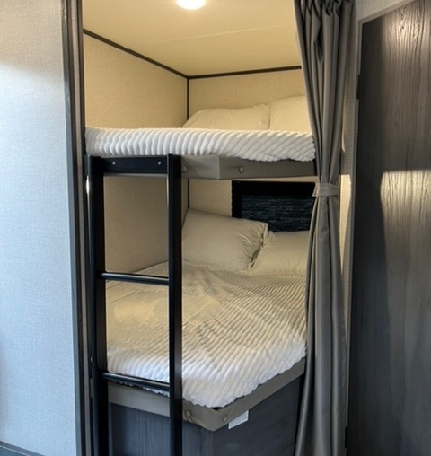 Discover comfortable sleeping in this RV rental's bunk beds. Features include a ladder, soft white bedding, and compact design.. Dutchmen Aspen Trail 2021